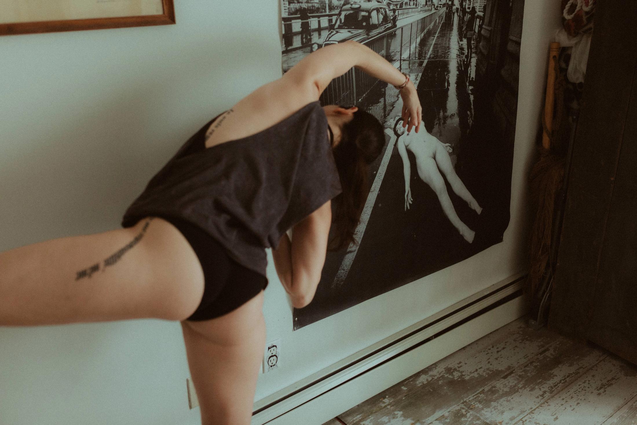 Maya bending forward in front of a large nude artwork.