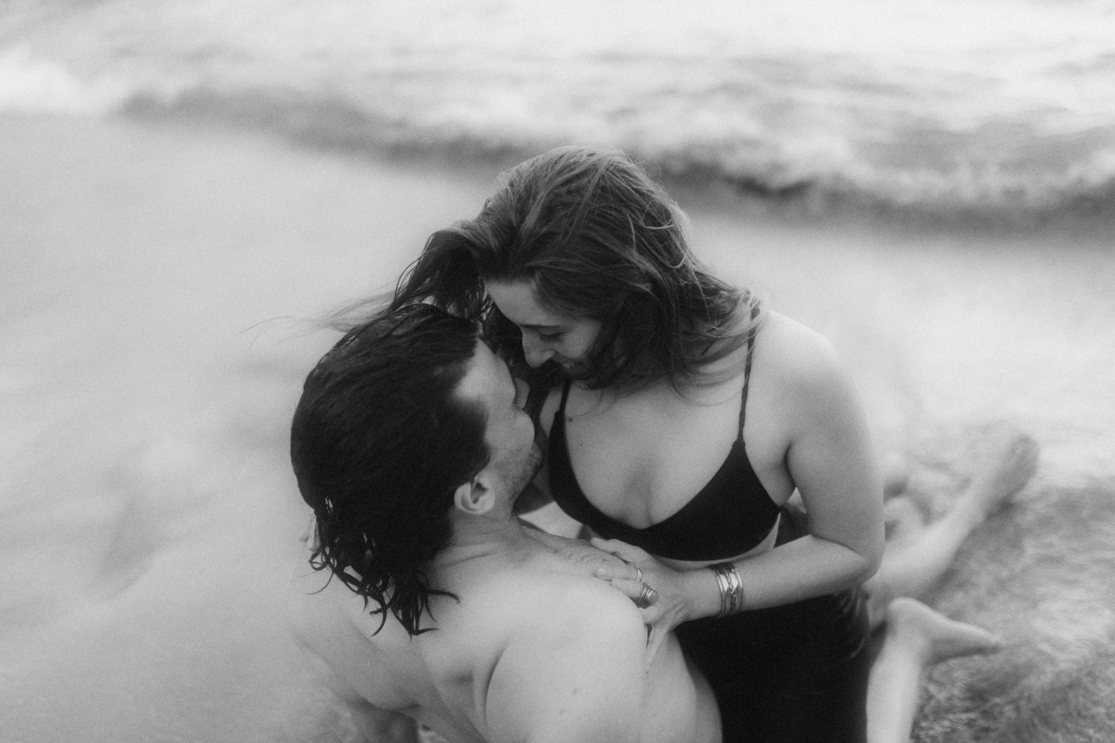Schwarz-weiß Foto eines küssenden Paars, Wasser läuft der Frau über den Rücken, Hafenliebe
