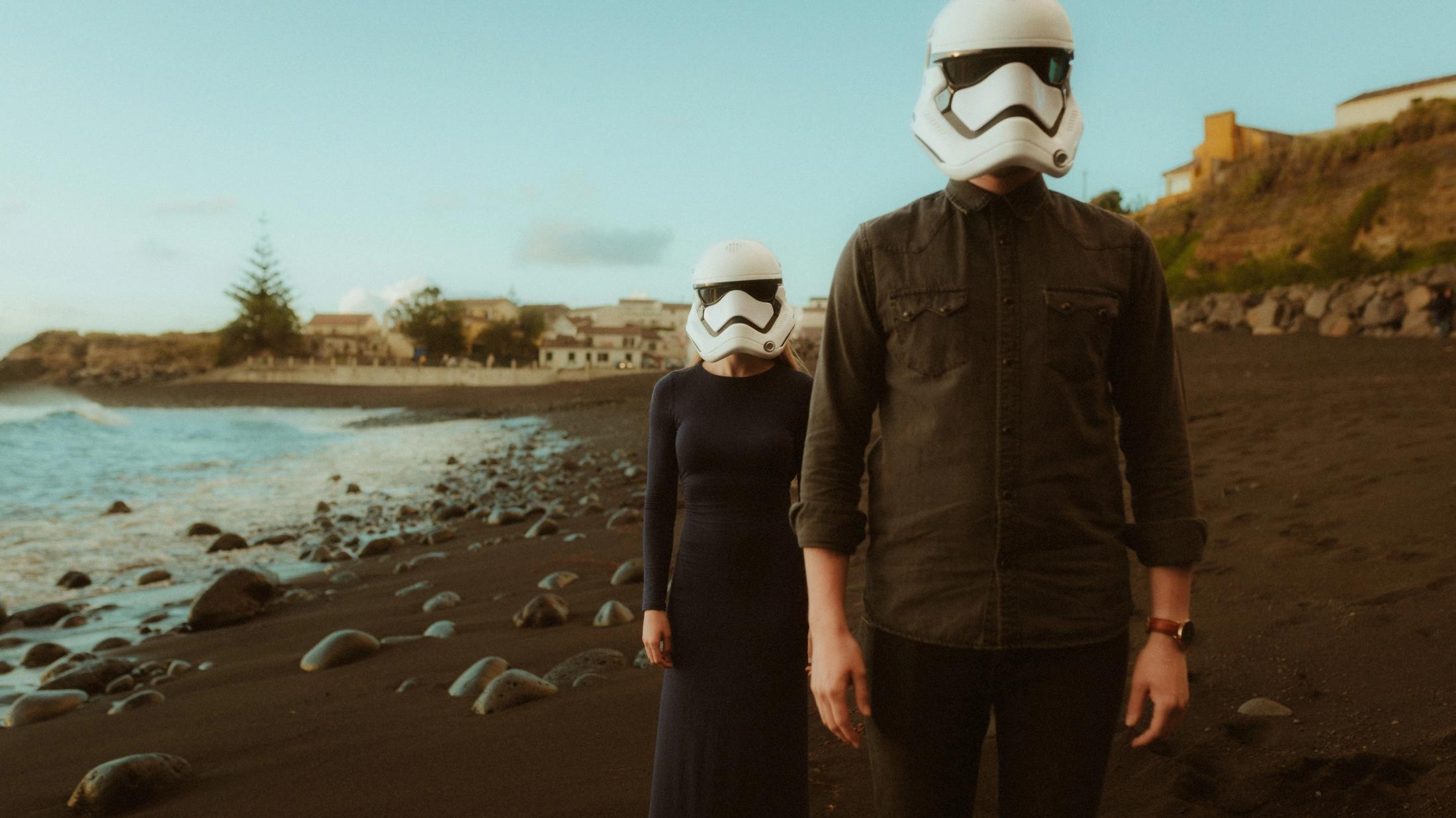 Two masked guests stand together on the beach after the ceremony.