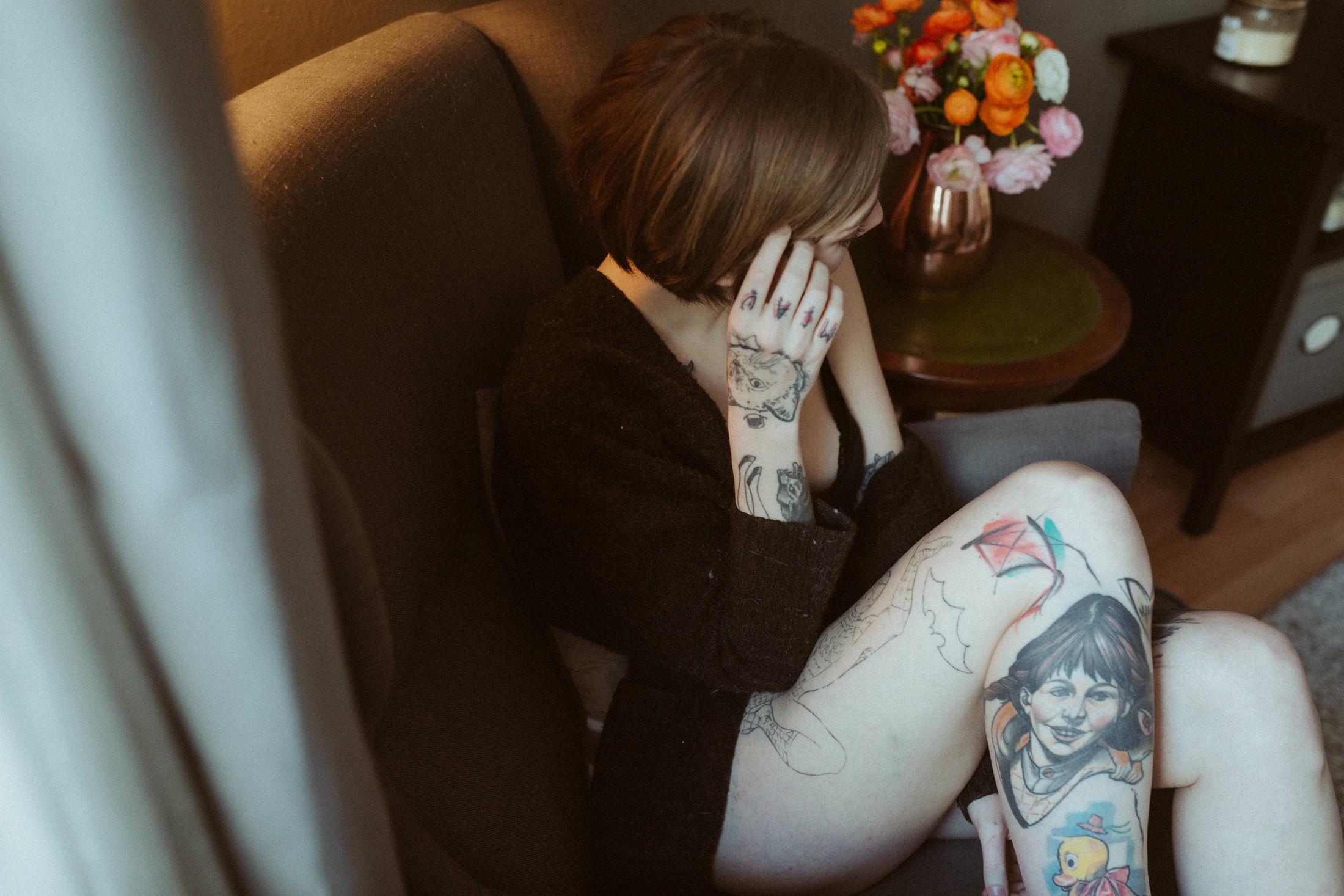 Anki covers part of her face with a tattooed hand.