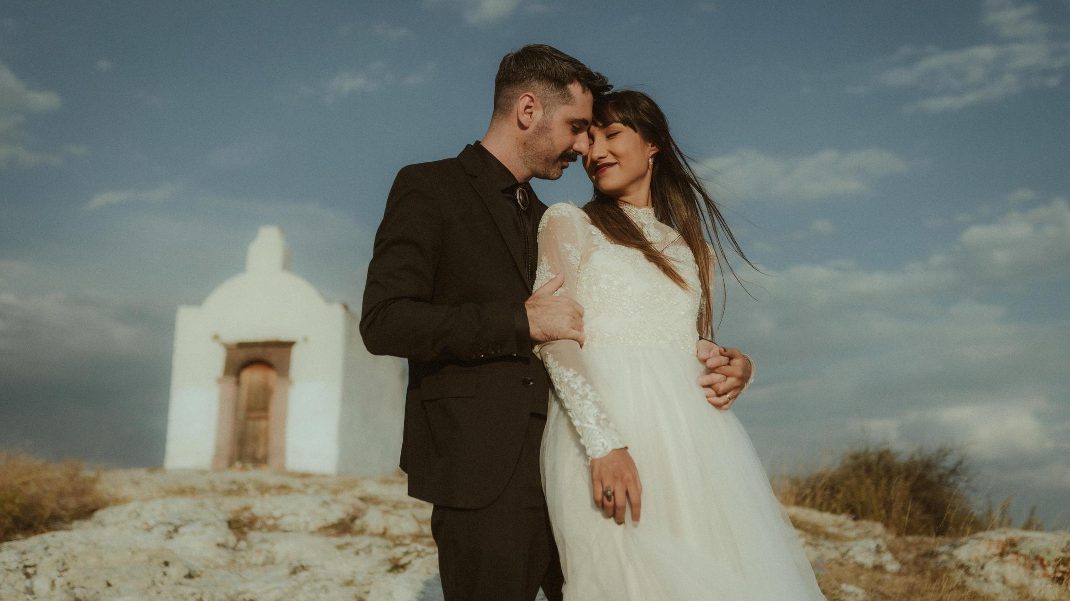 Anna und Nahuel stehen vor einer kleinen weißen Kapelle.