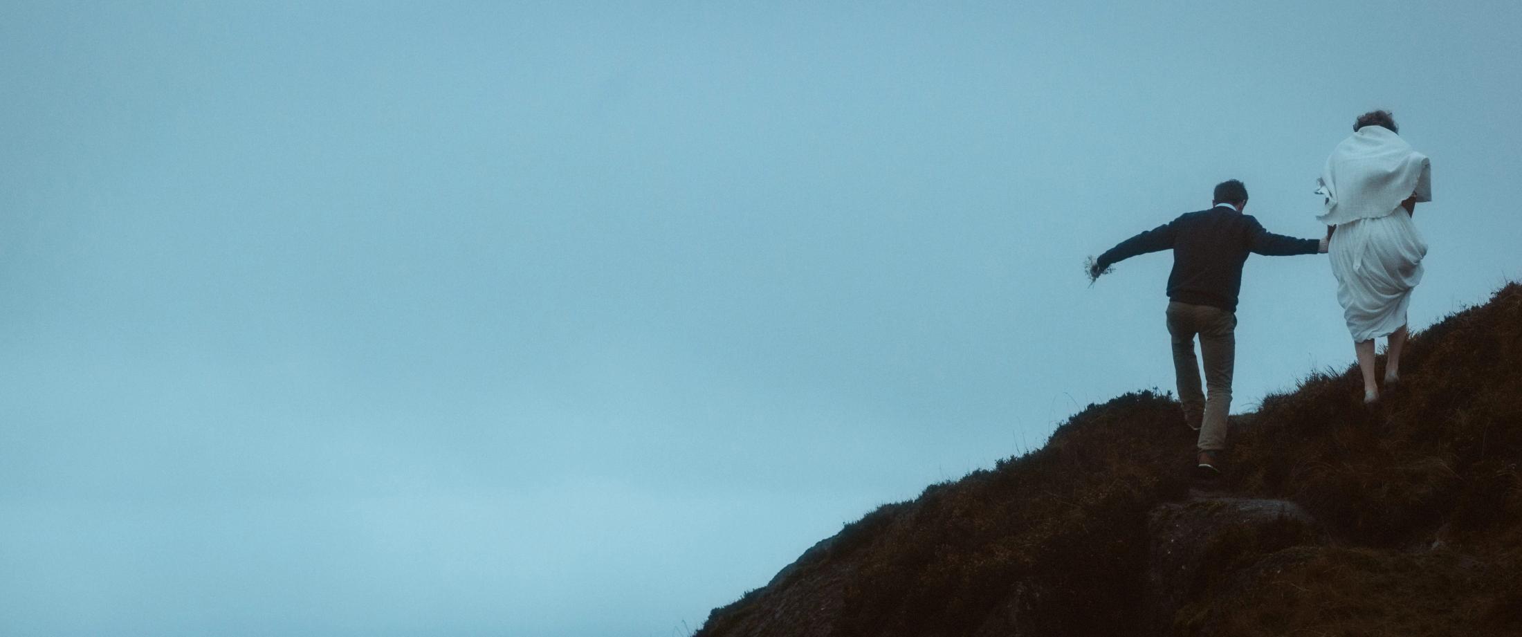 Jule und Rory steigen einen steilen Grashang in die tiefen Wolken der Cooley Mountains hinauf.