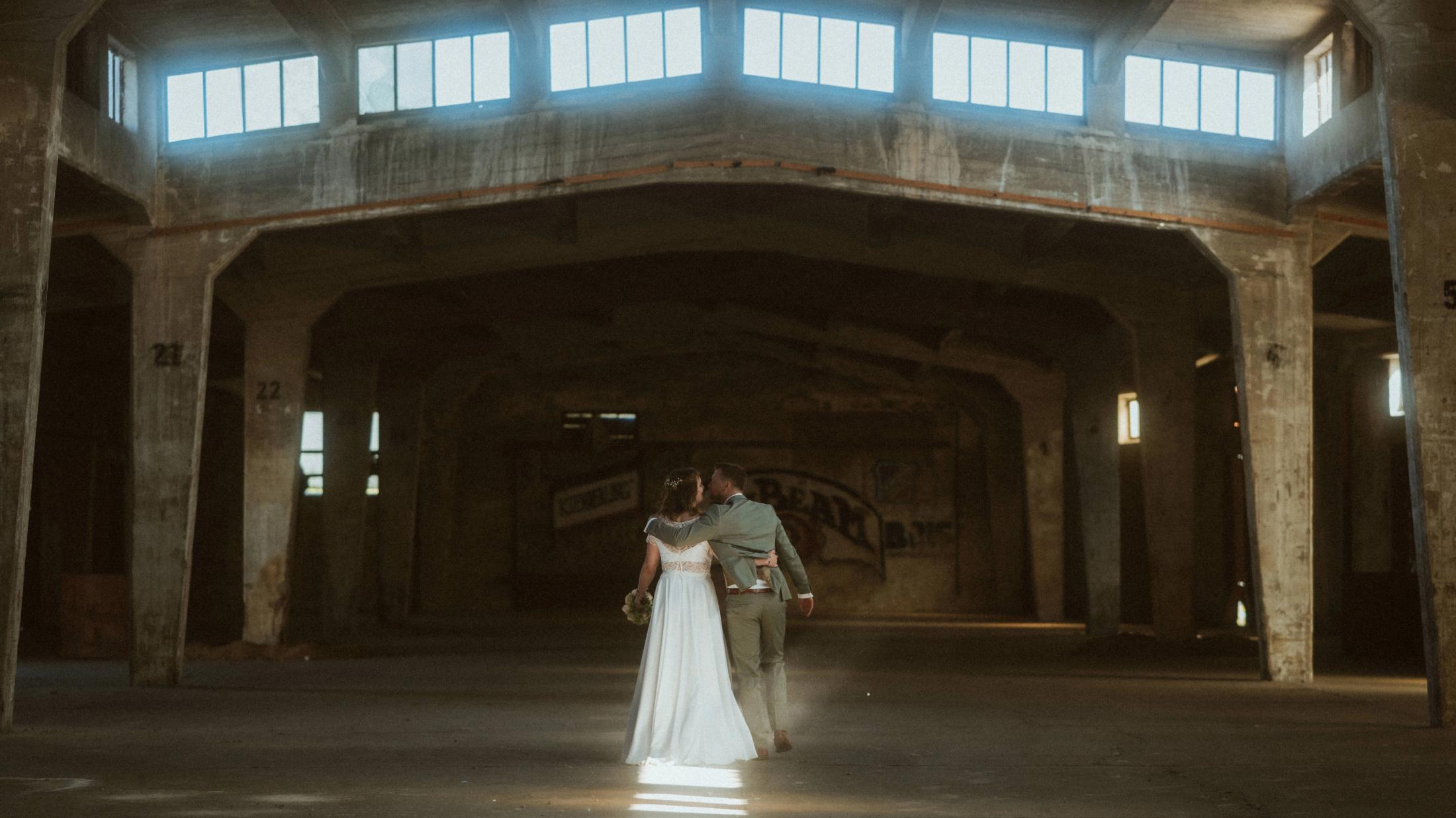 Kira and Jannick walk closely together through a vast industrial hall in Lübeck.