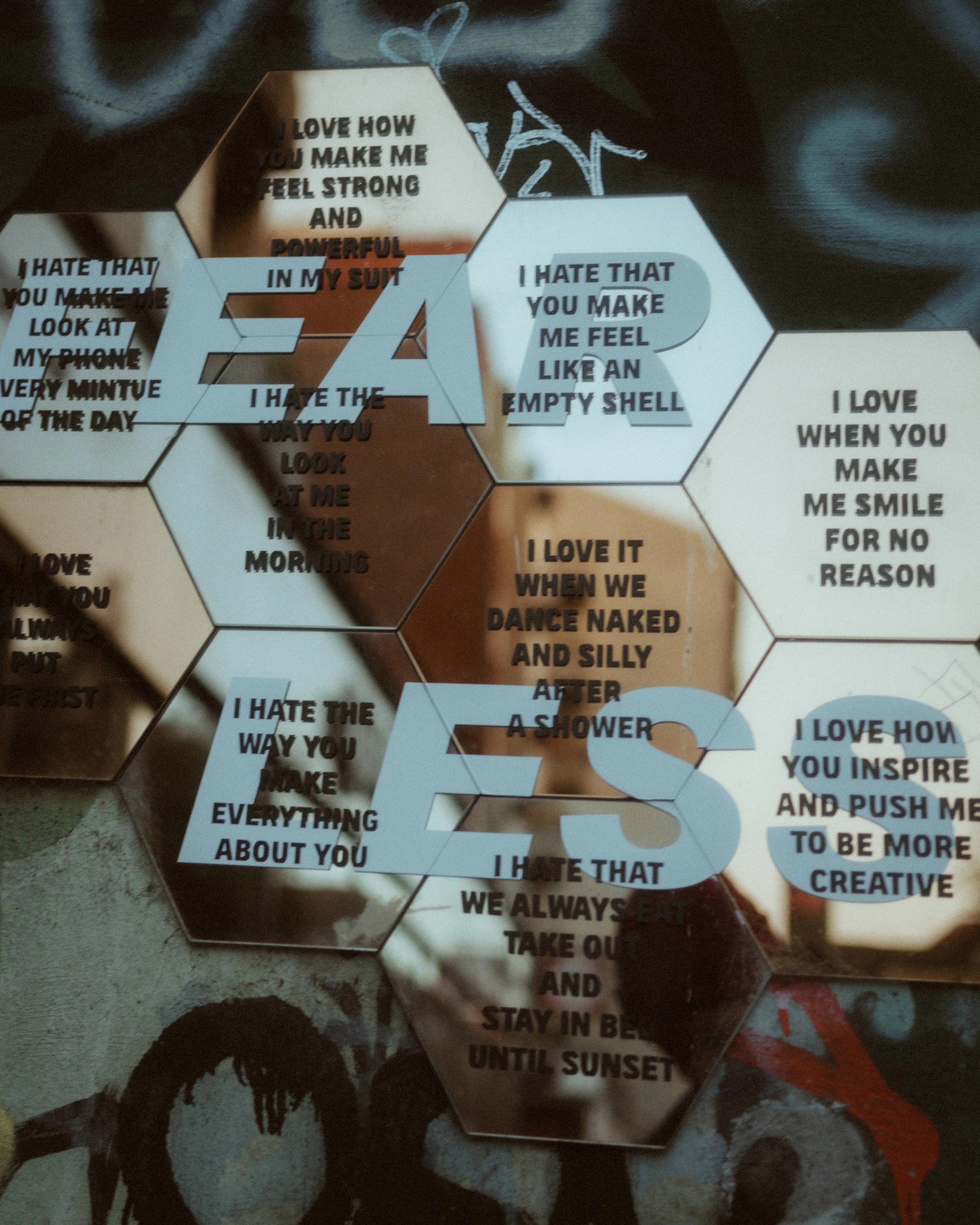 Reflections of the couple overlap hexagonal panels printed with phrases about love and irritation.