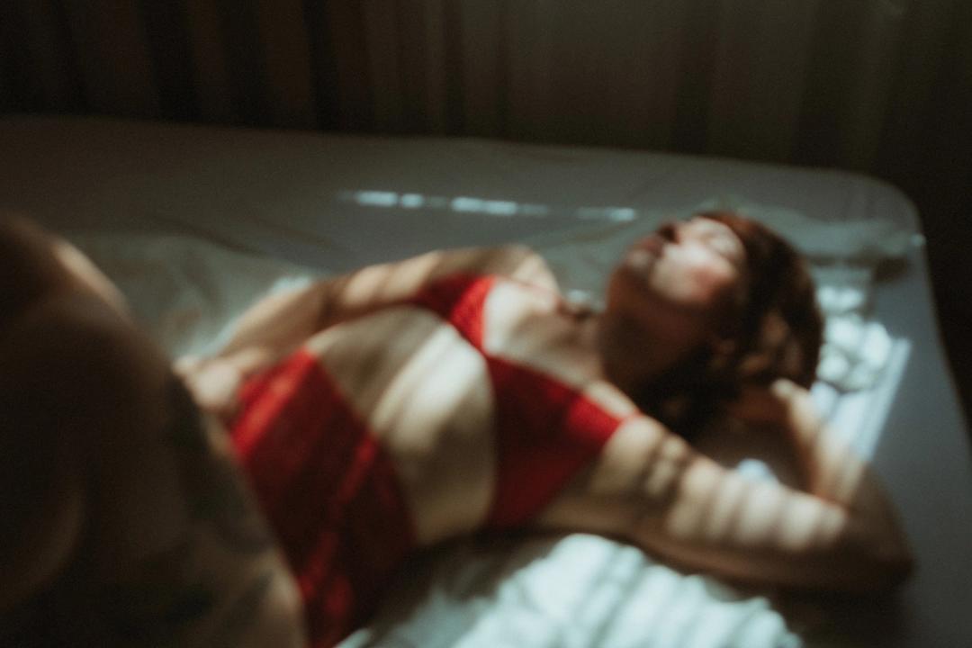 A reclining portrait with red fabric and muted daylight