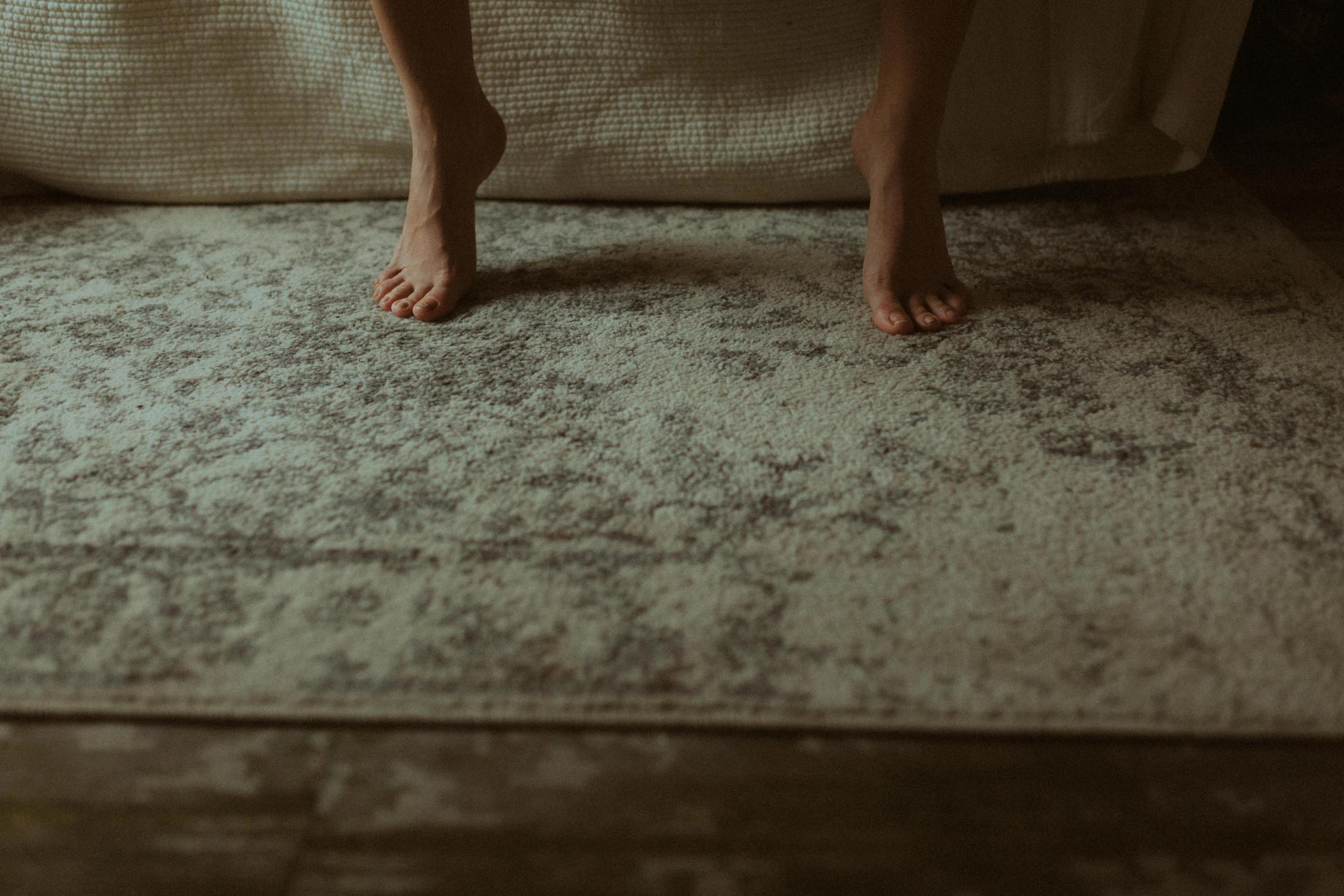 Maya’s bare feet resting on the apartment rug.