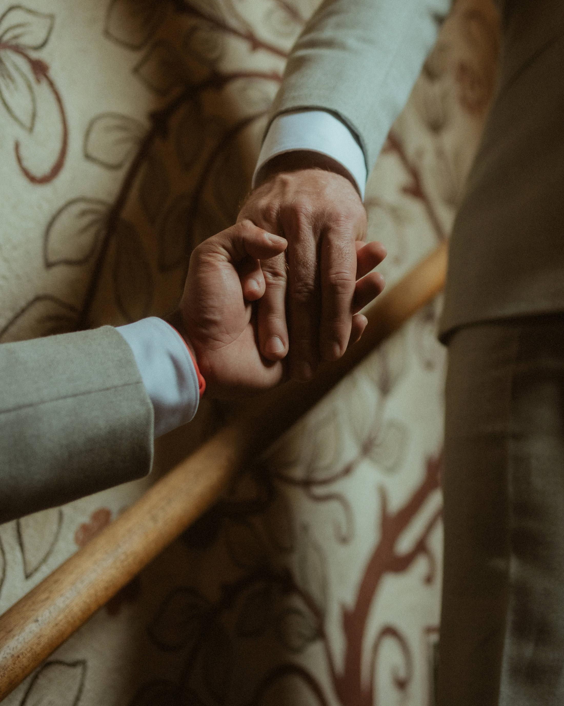 Close view of their hands meeting on a carved wooden railing.