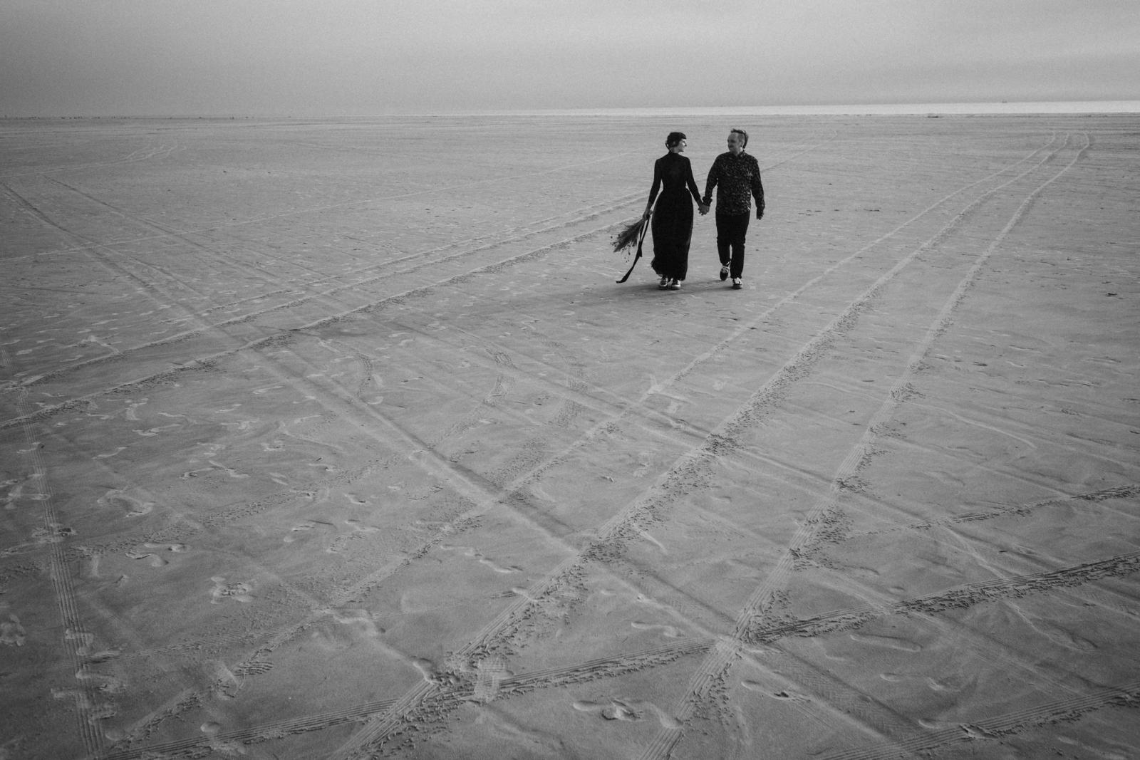 Bjørn and Jana walking across the wide beach in St. Peter-Ording one year after their wedding