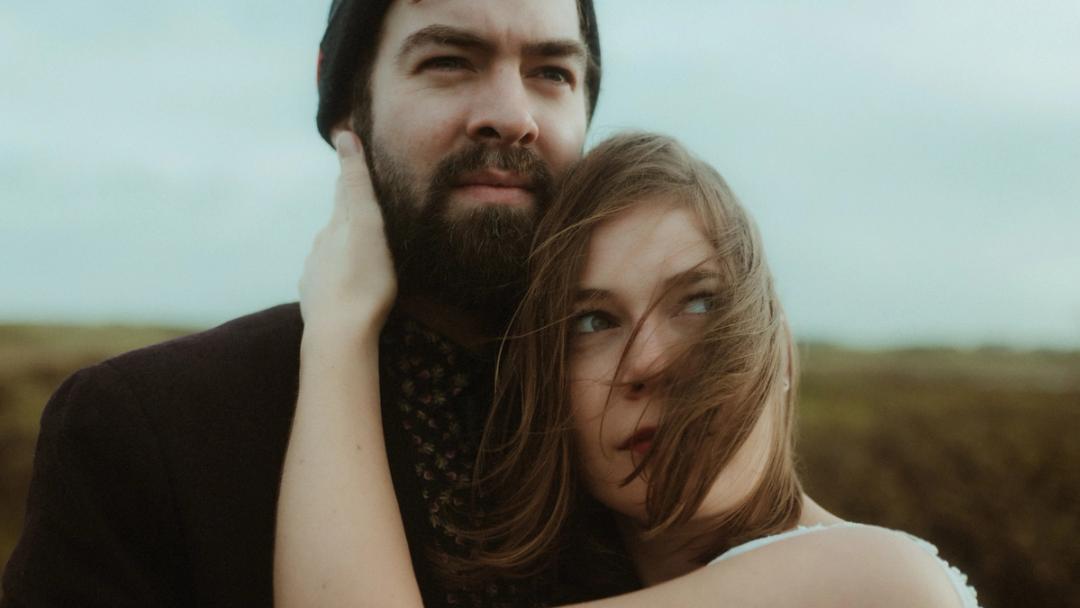 Close portrait of Anni and Daniel with her hair blown across her face.