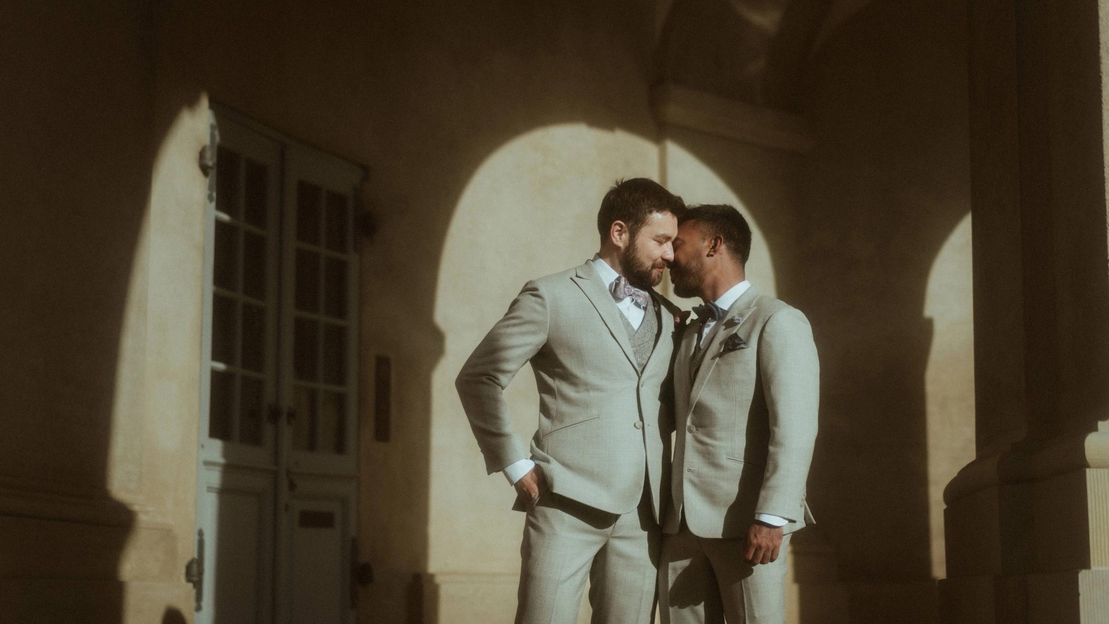 Kris and Ilya lean together while their shadows fall across a pale wall.