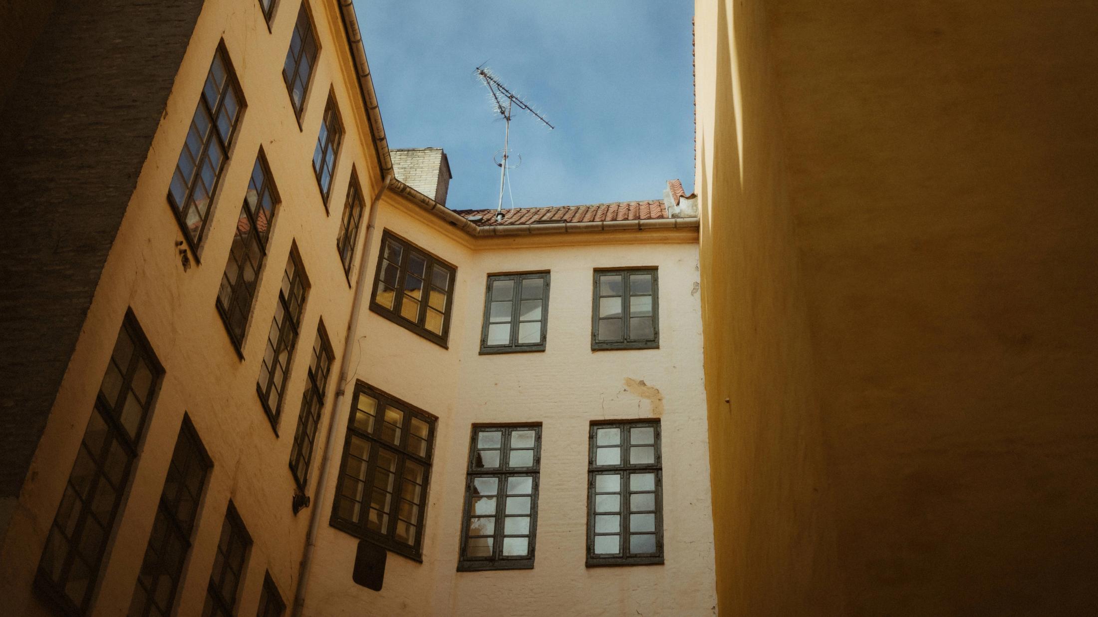 Warm light falls across angular Copenhagen facades and an empty courtyard.