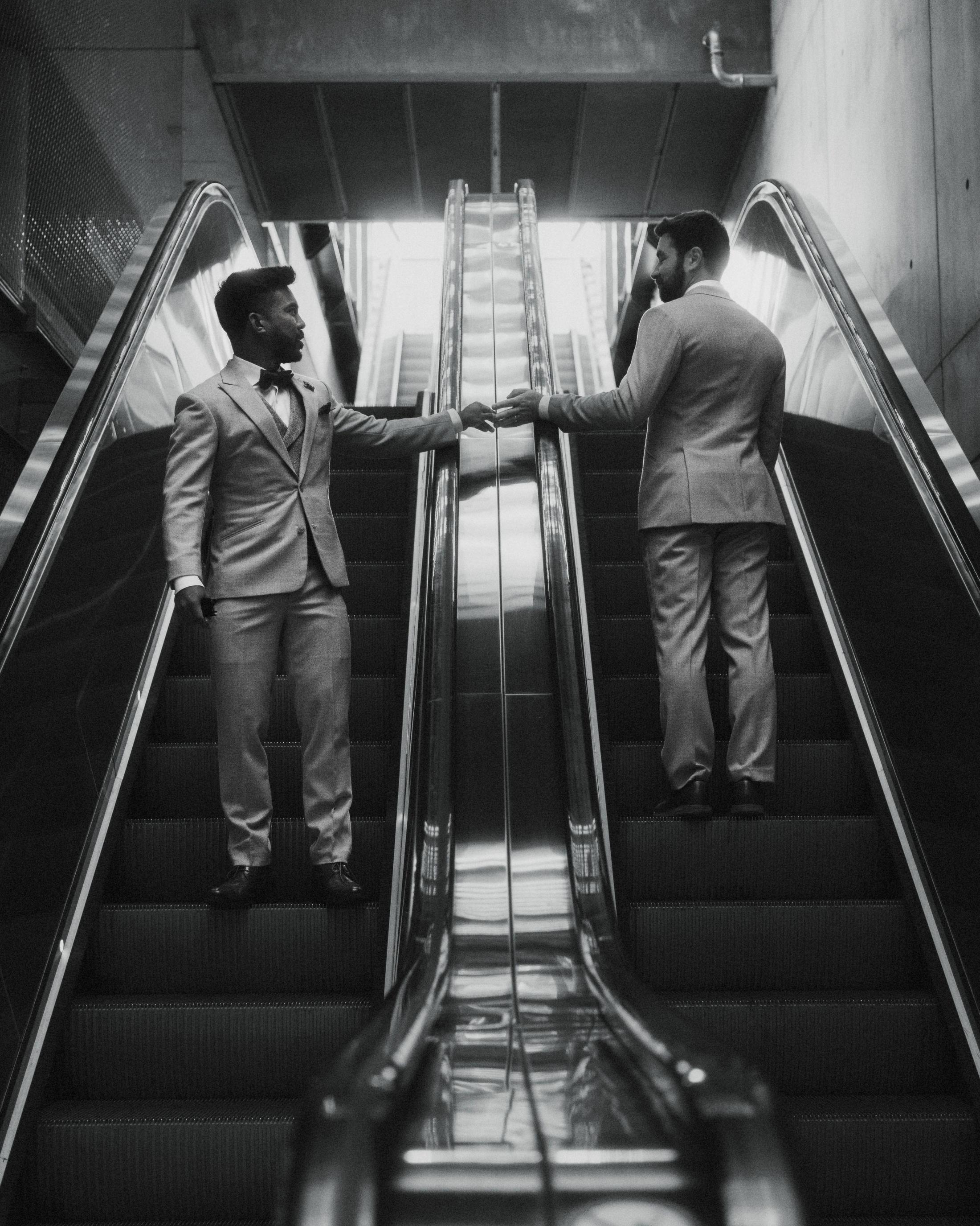 Black-and-white view of Kris and Ilya on opposite sides of an escalator.