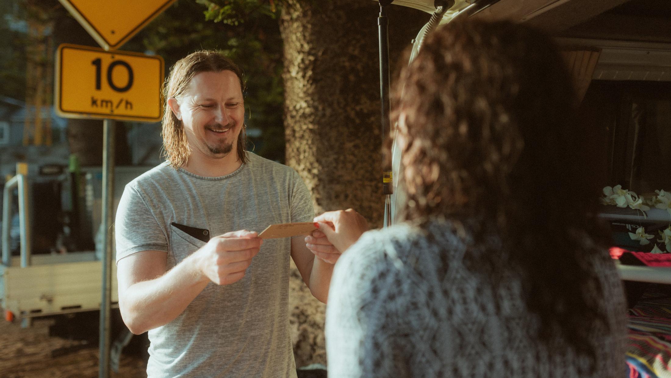 Roman reading a card while Petra stands in front of him
