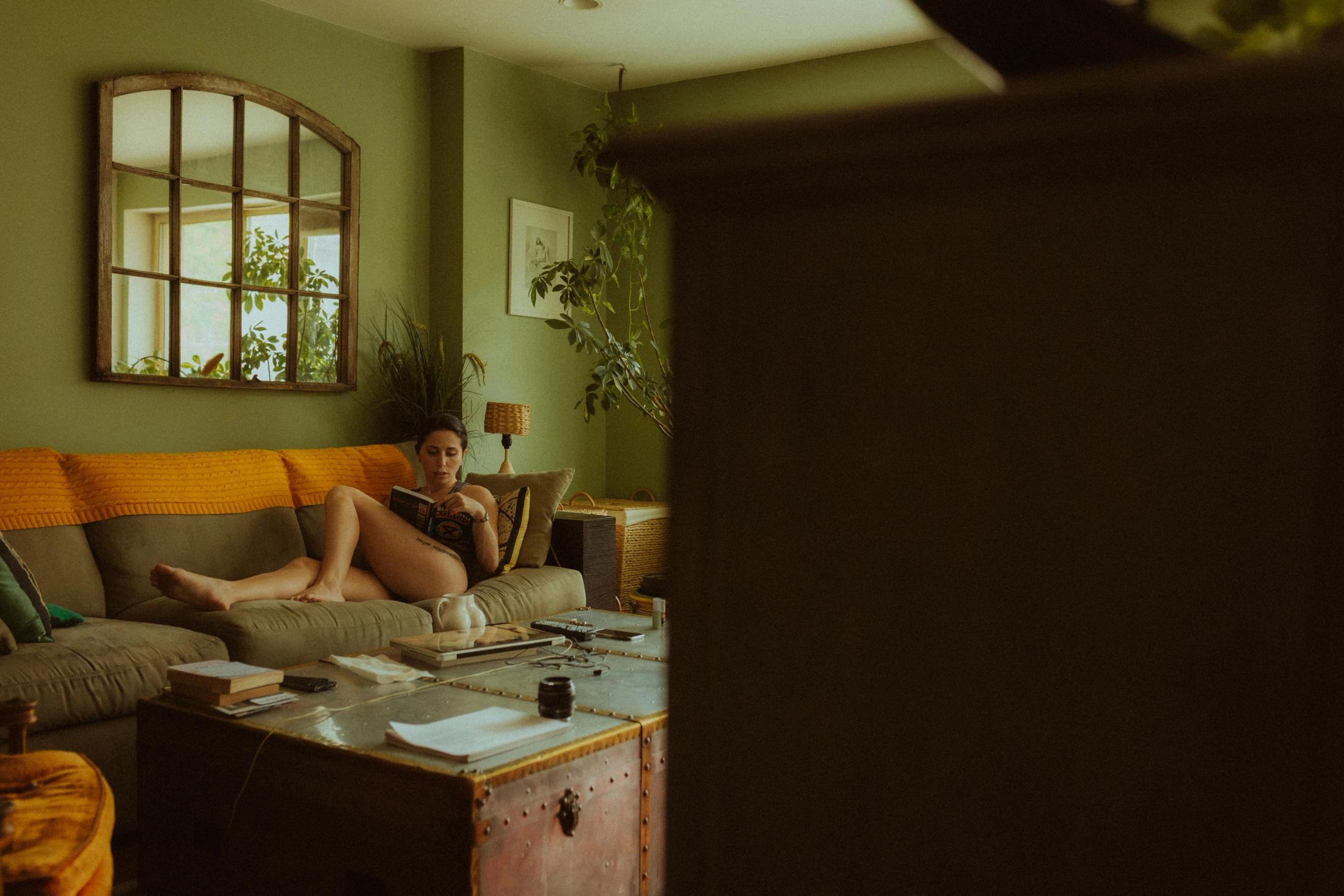 Wide view of Maya reclining in the lived-in apartment.