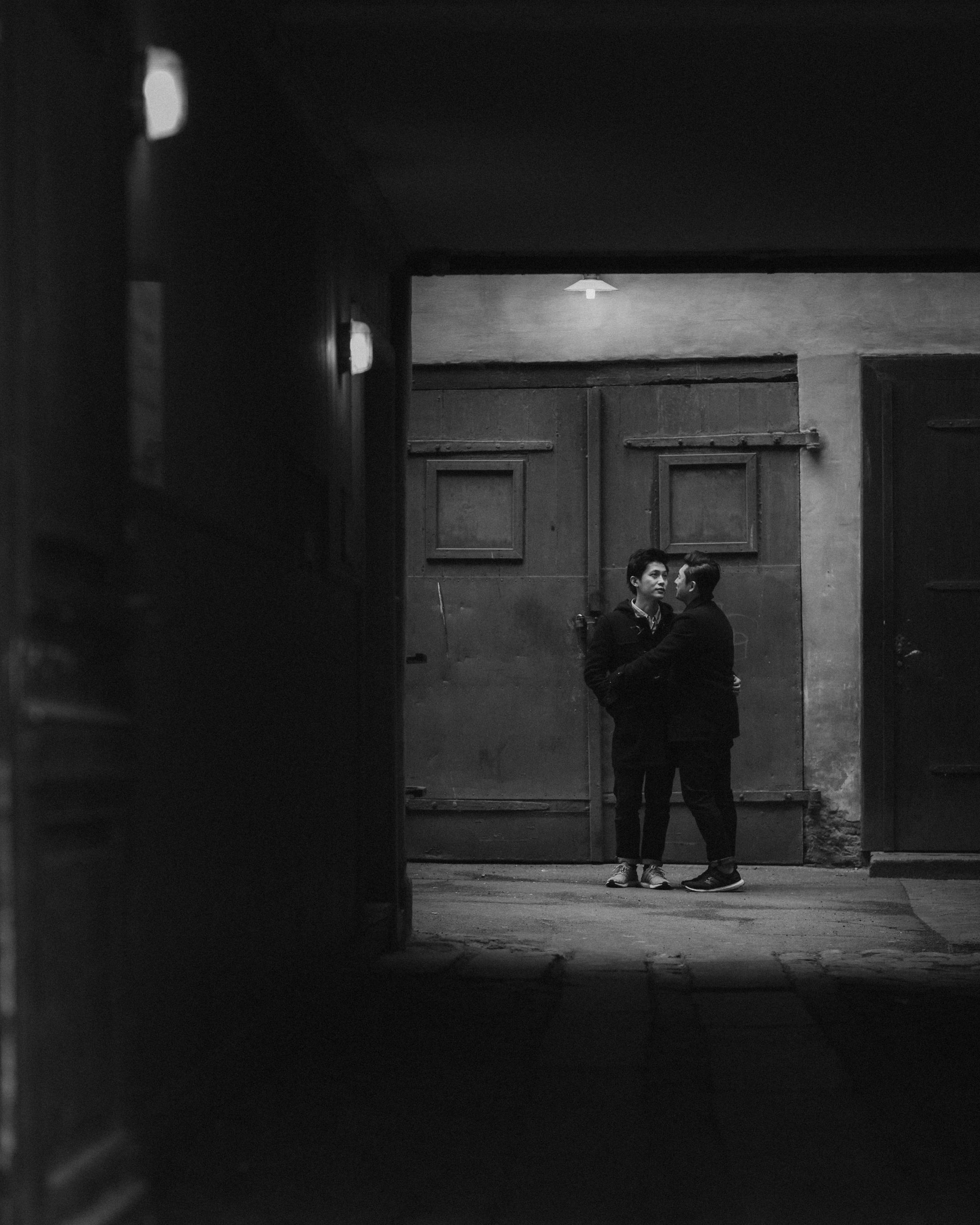 Kevin and Terence stand together inside a dark doorway.