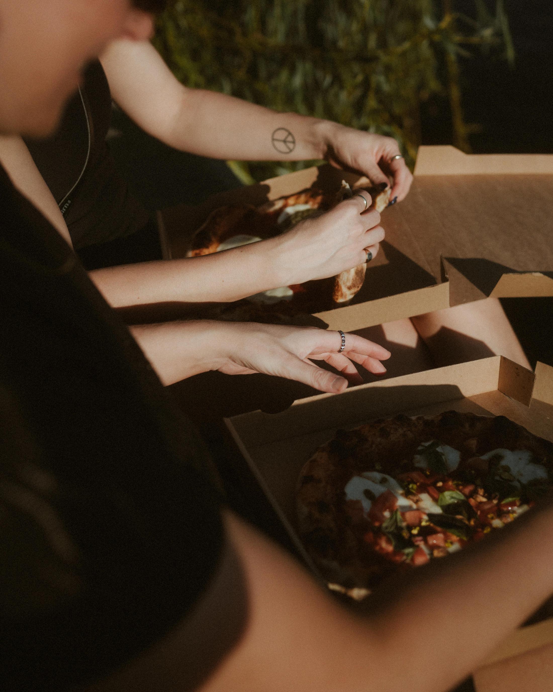 Hands opening a pizza box beside the canal.