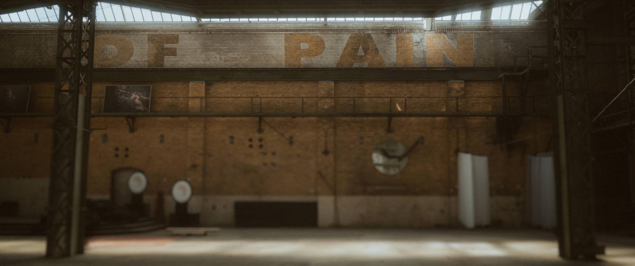 The empty industrial hall at Mahalla with the PAIN lettering above the far wall.