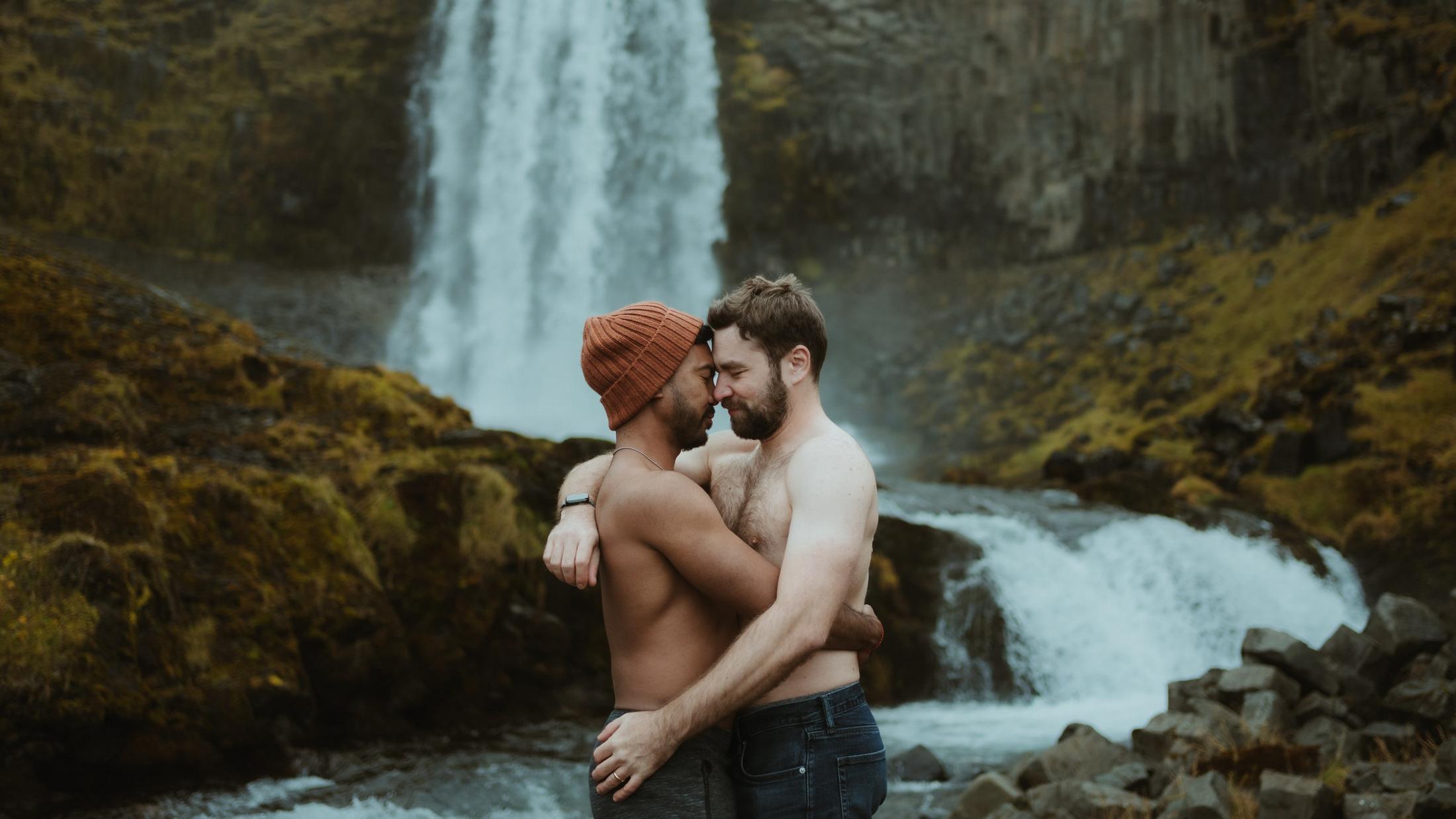 Two people embracing beside a waterfall.