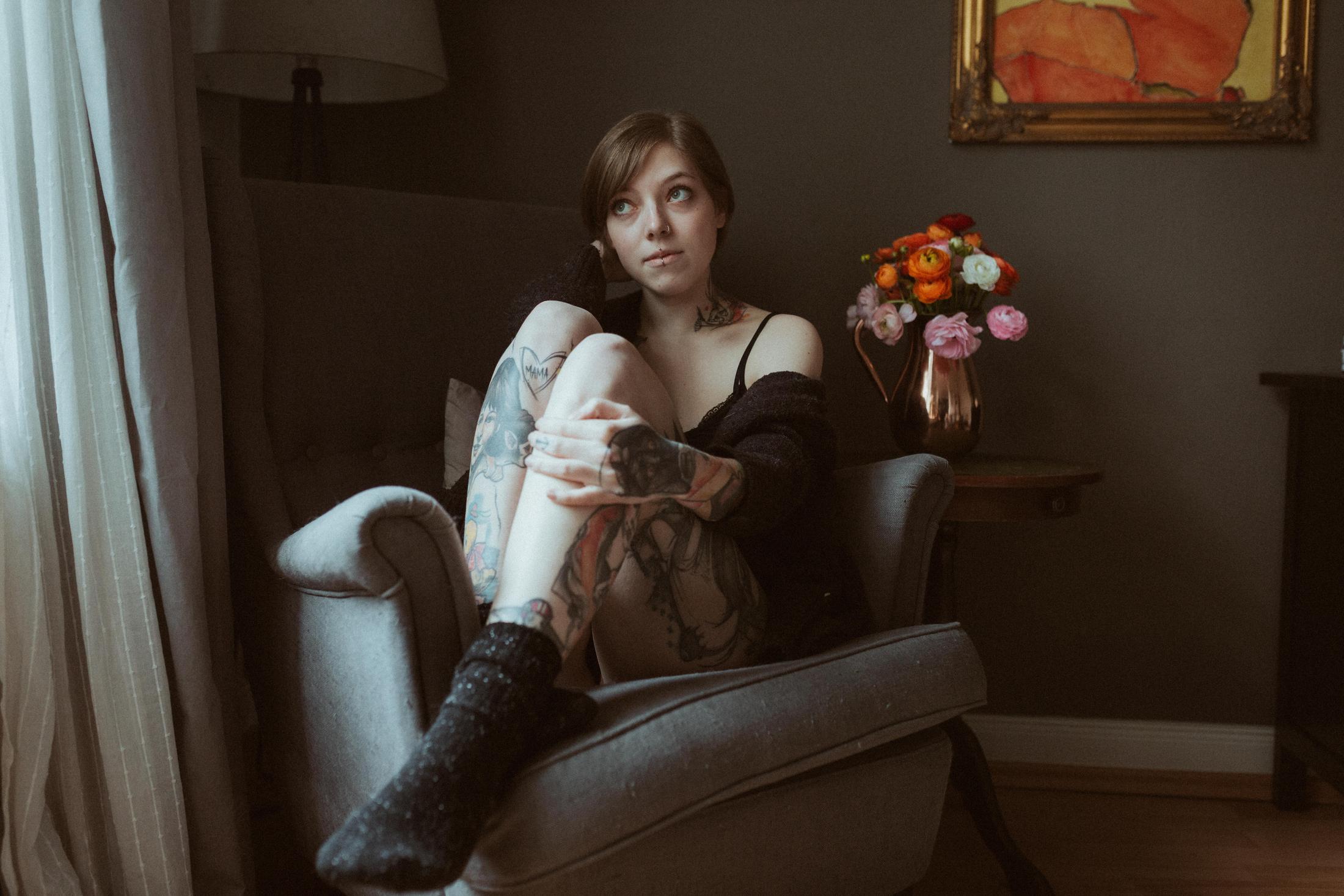 Anki sits in an armchair surrounded by art and flowers.
