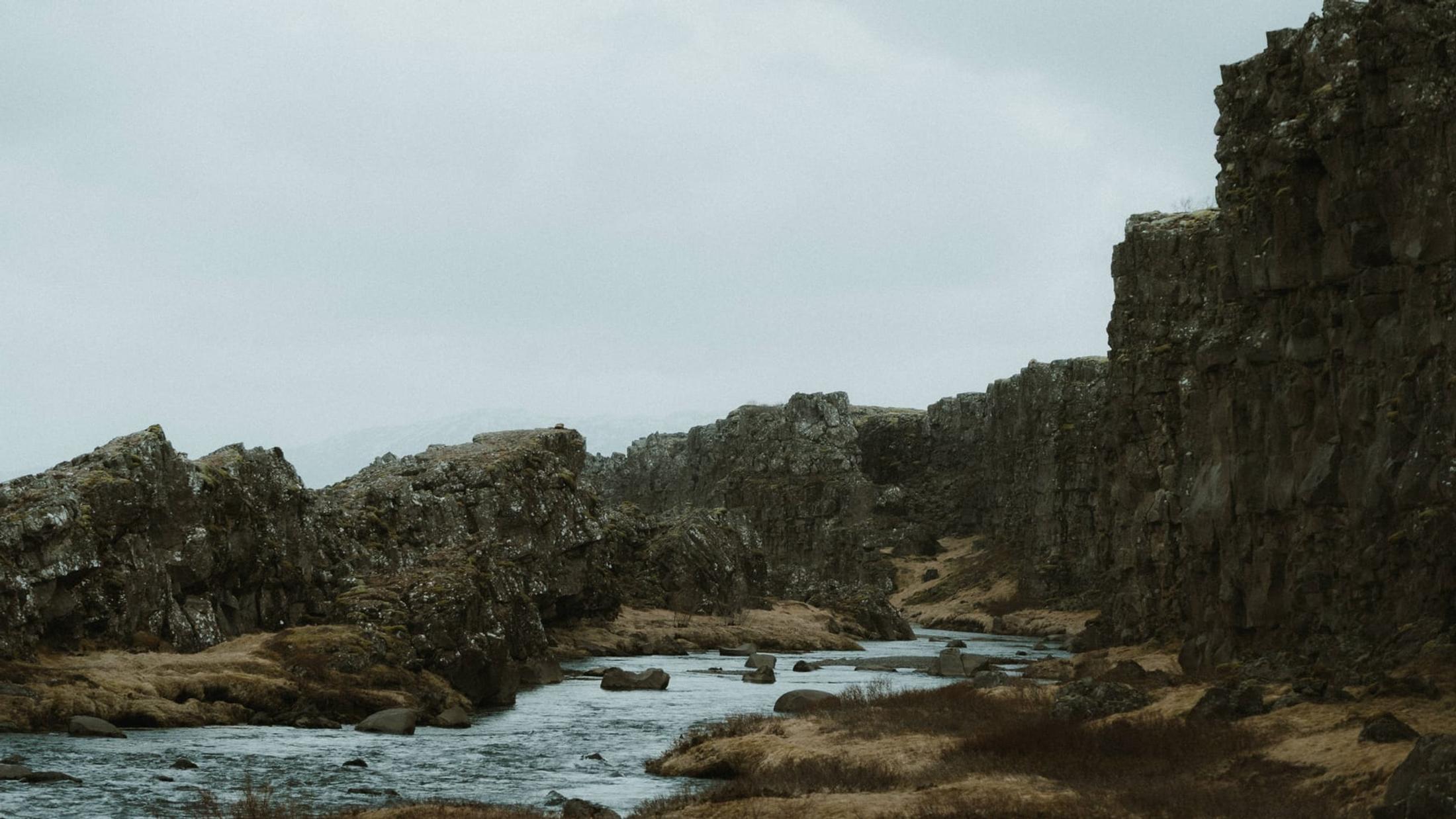 A river flowing between dark rock walls in Þingvellir.