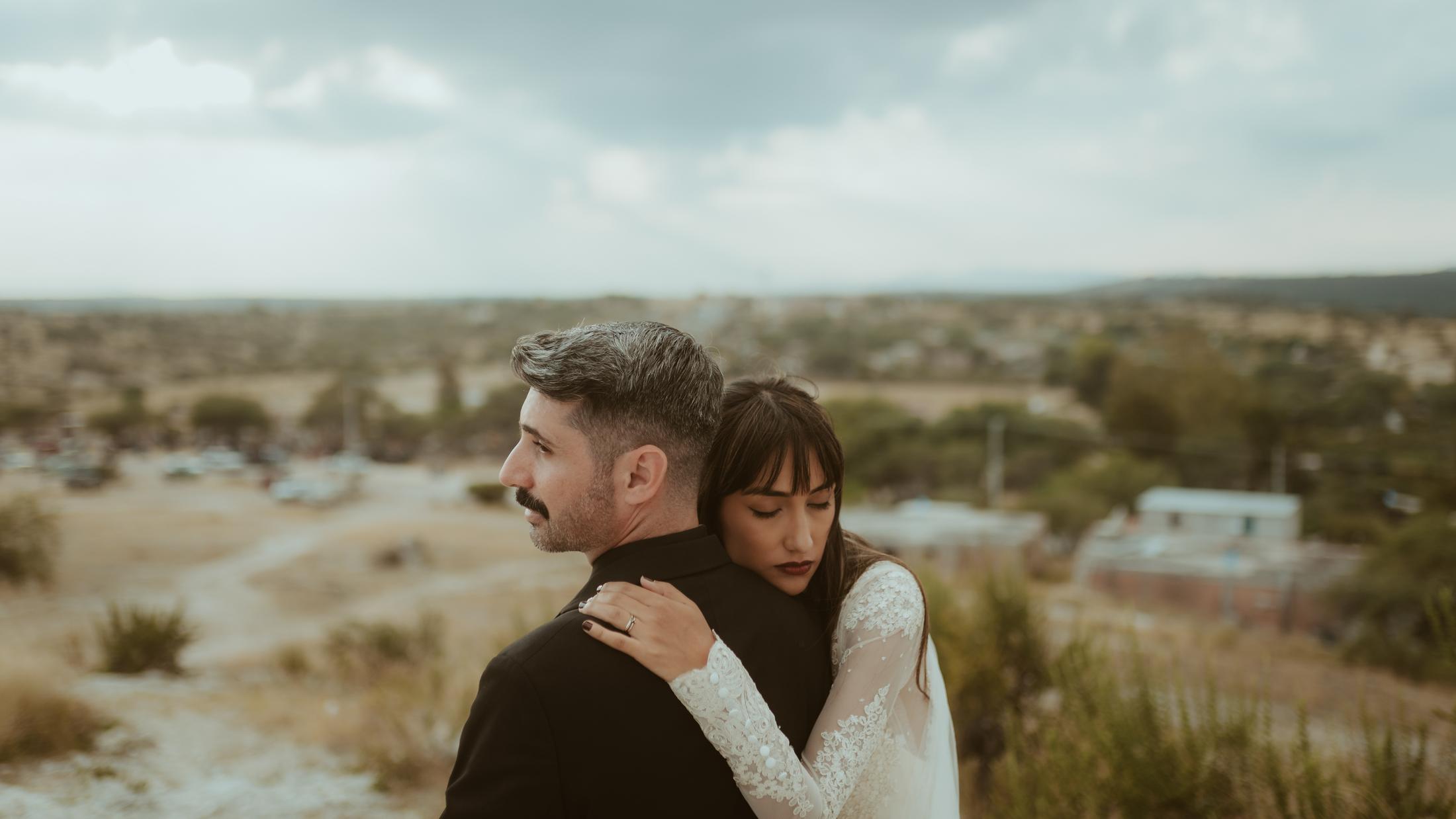 Anna und Nahuel umarmen sich an einem Hang.