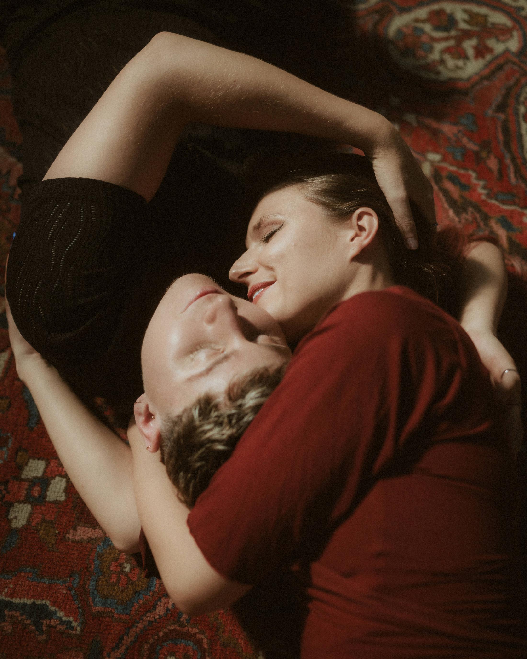 Noah and Michéle lying close together on a red carpet