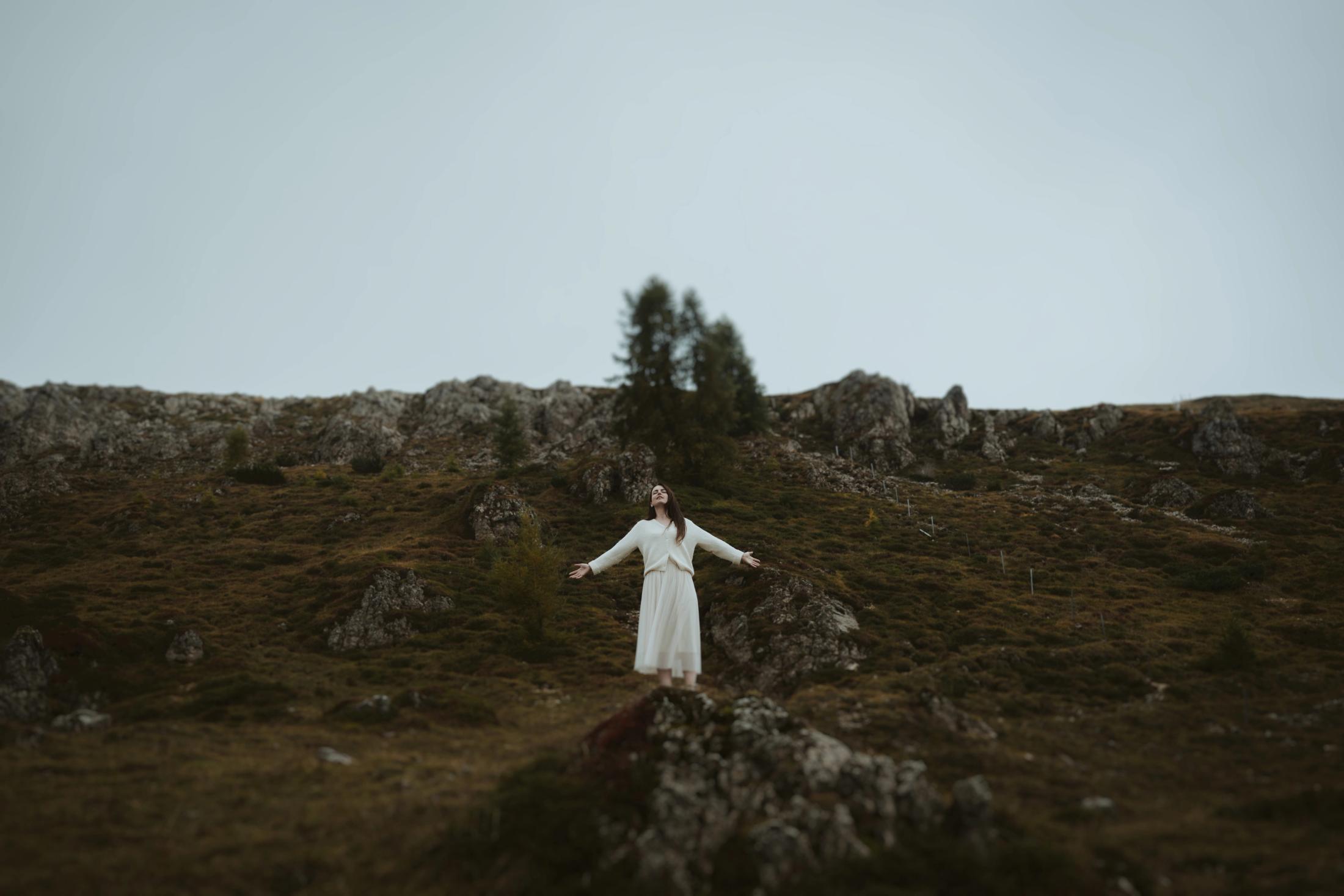 Jana standing on the mountain with her arms open in the fog.