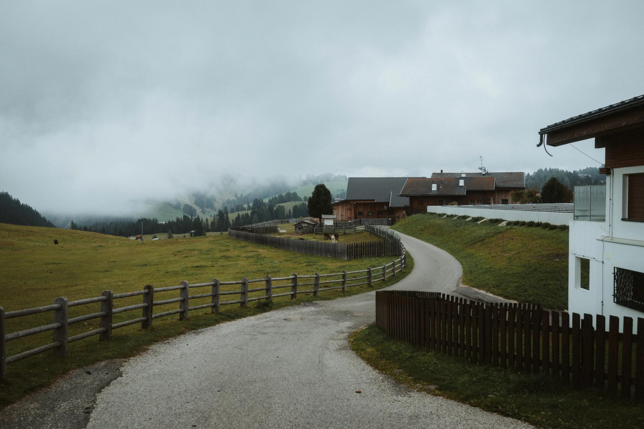 A narrow road leading through an alpine village beneath low cloud.