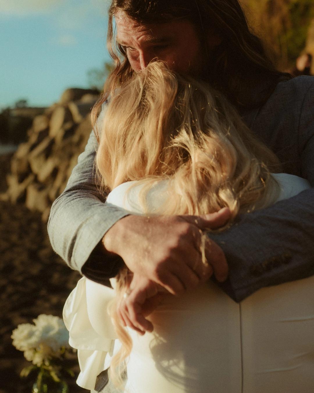 Twyla and Gary hold each other closely on the black sand.