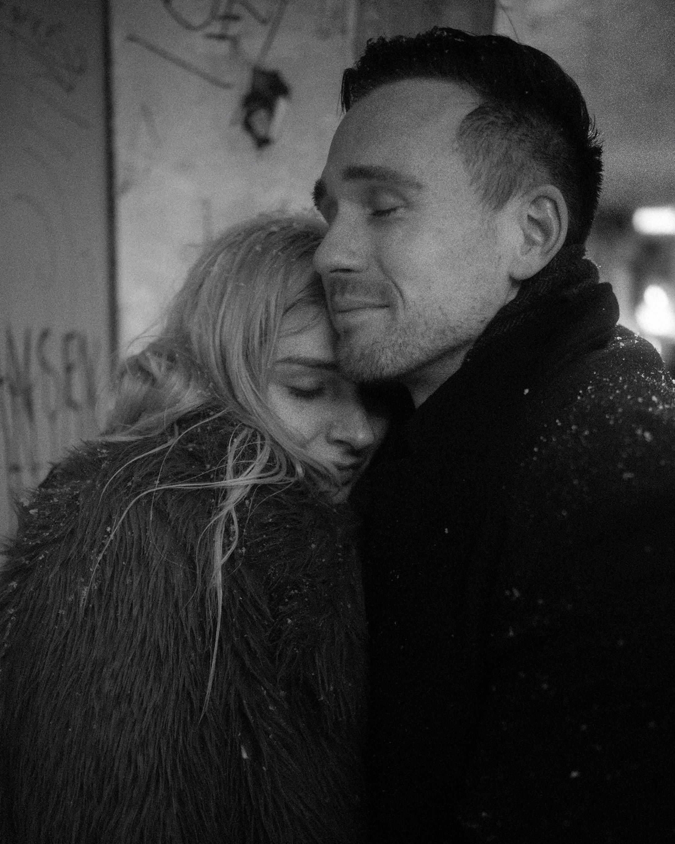 Lorelai rests against Steffen in the snow, both smiling in black and white.