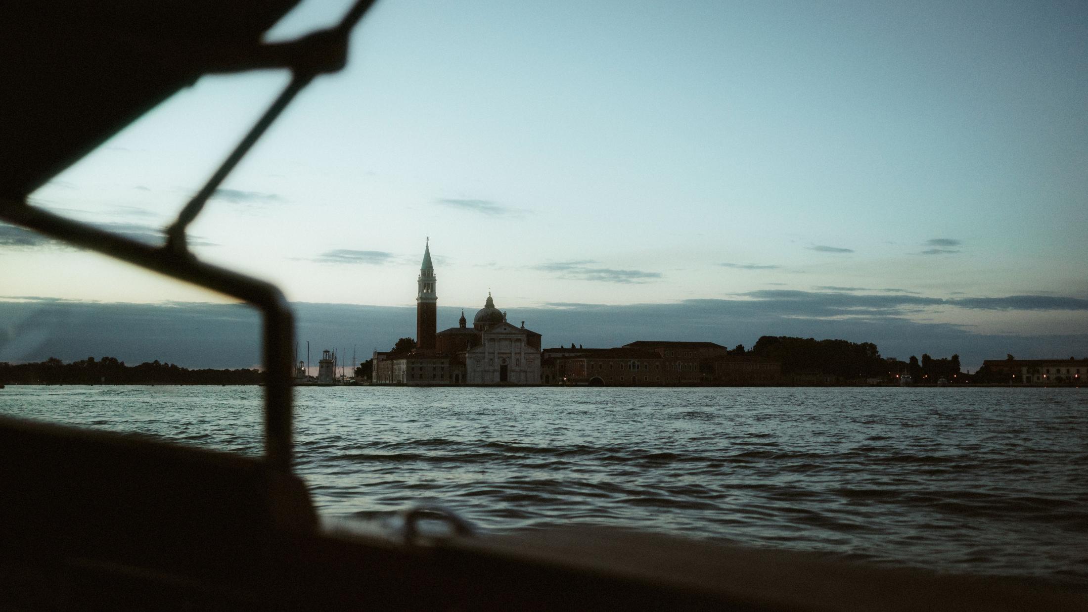 The Venetian lagoon and a distant church are framed by the structure of a boat.