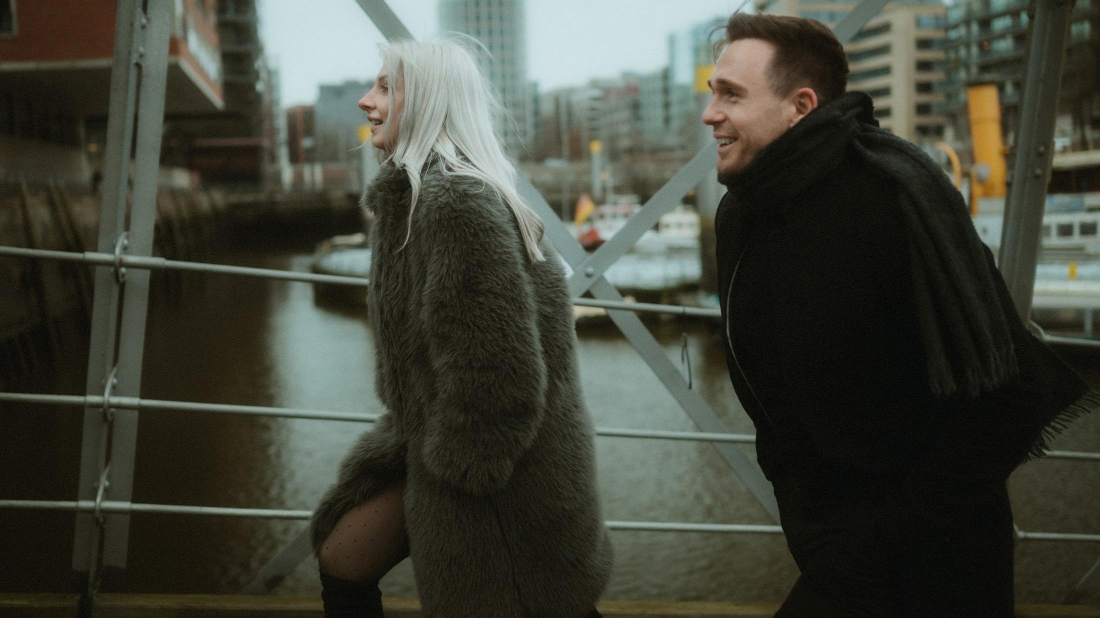 Lorelai and Steffen laugh together against the industrial harbour setting.