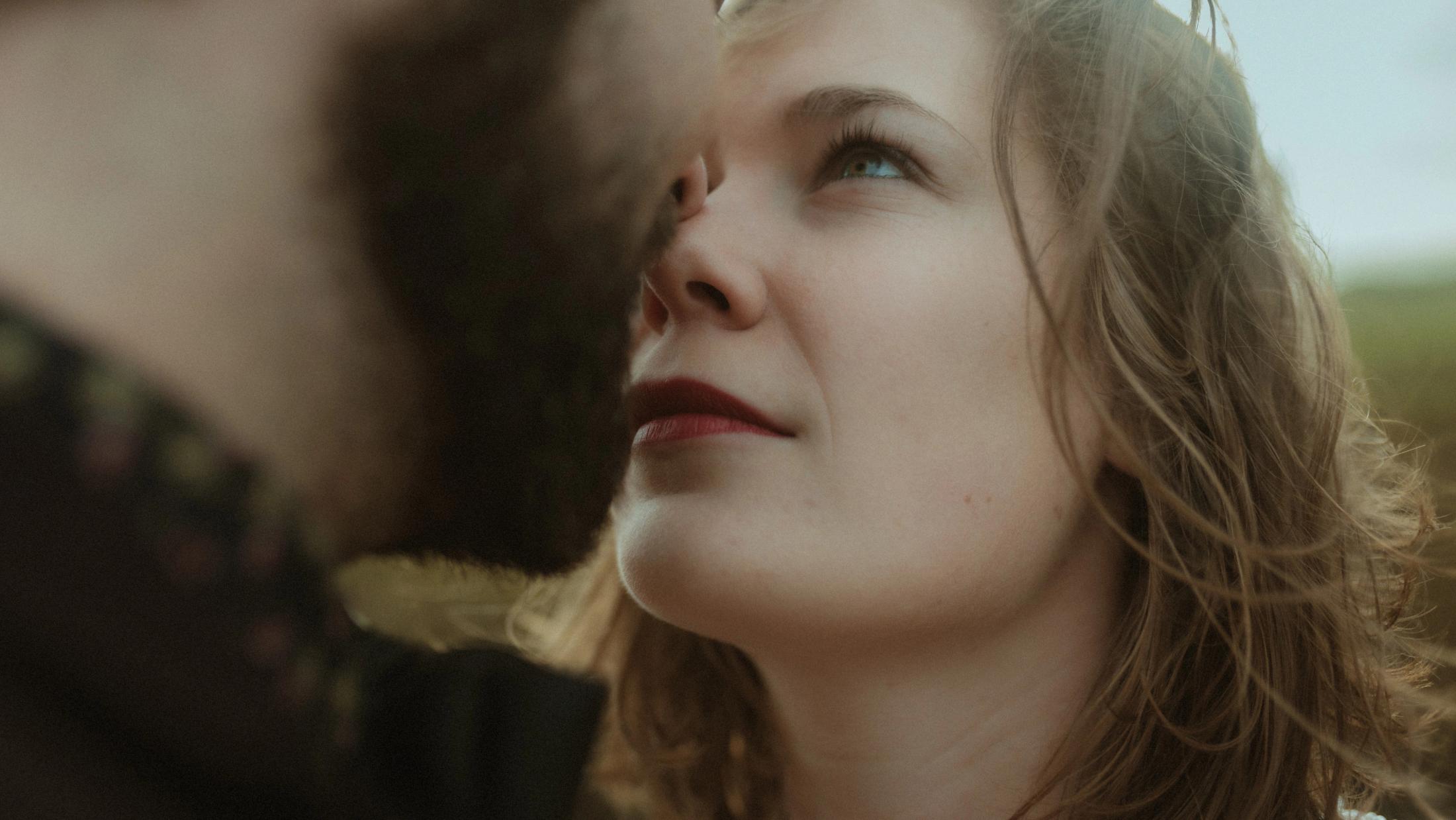 Anni looks up toward Daniel in a close windswept portrait.