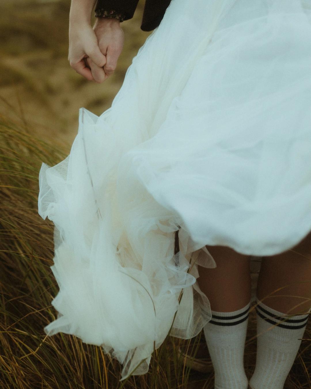 White dress, pulled-up socks and light shoes among the dune grass.