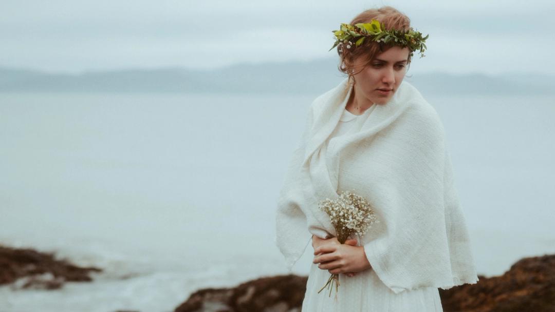 Porträt von Jule mit Blumenkranz vor der gedämpften irischen Küste.