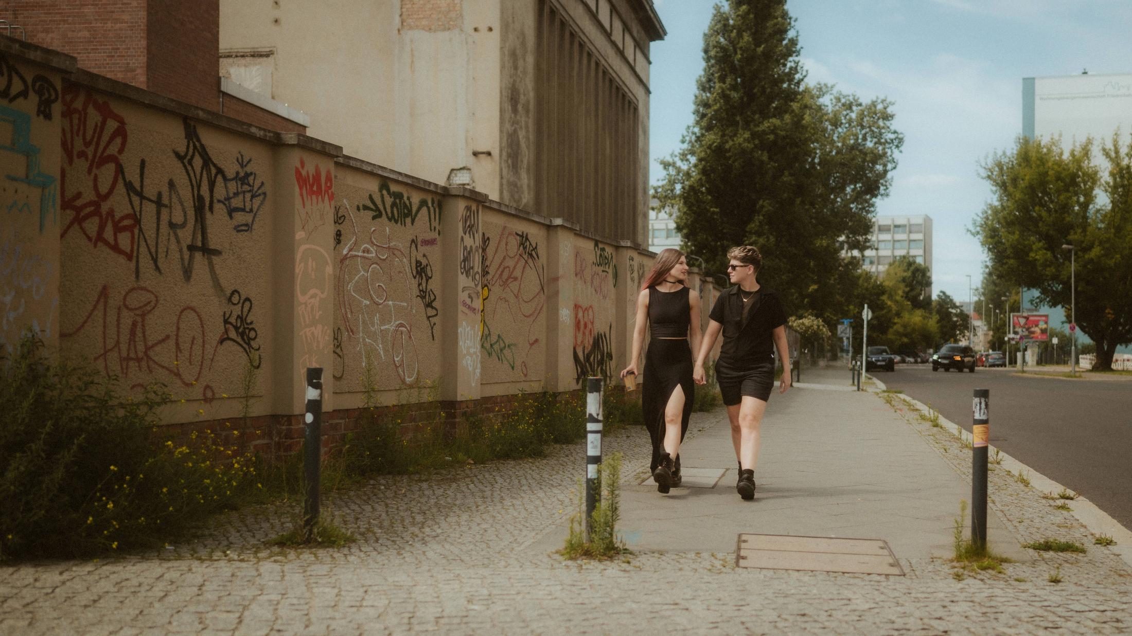 Noah and Michèle walking away hand in hand along the graffiti wall.