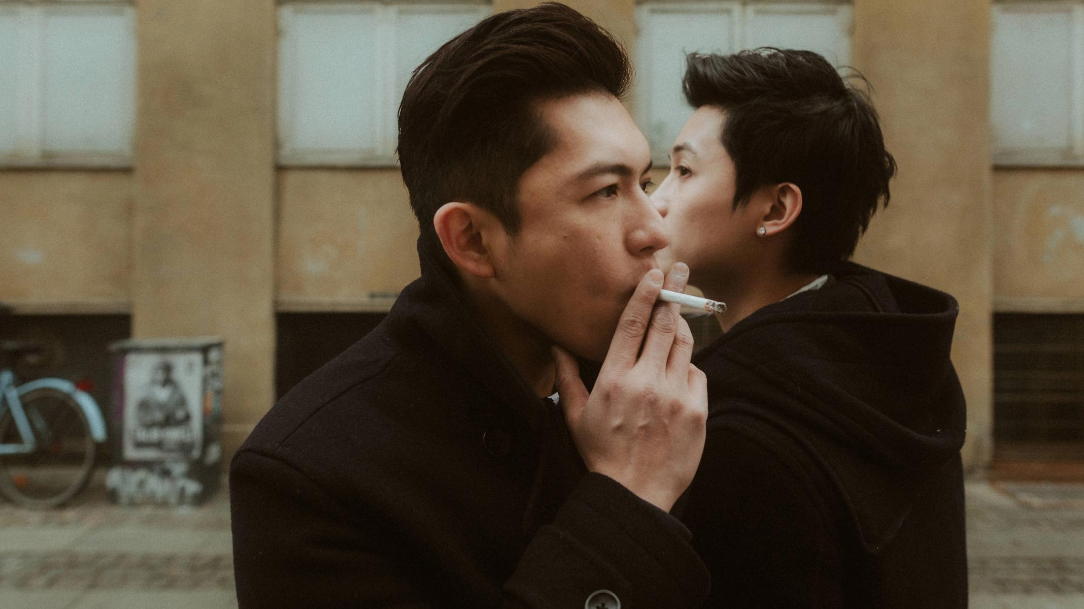 One of the men lights the other’s cigarette during their Copenhagen portraits.