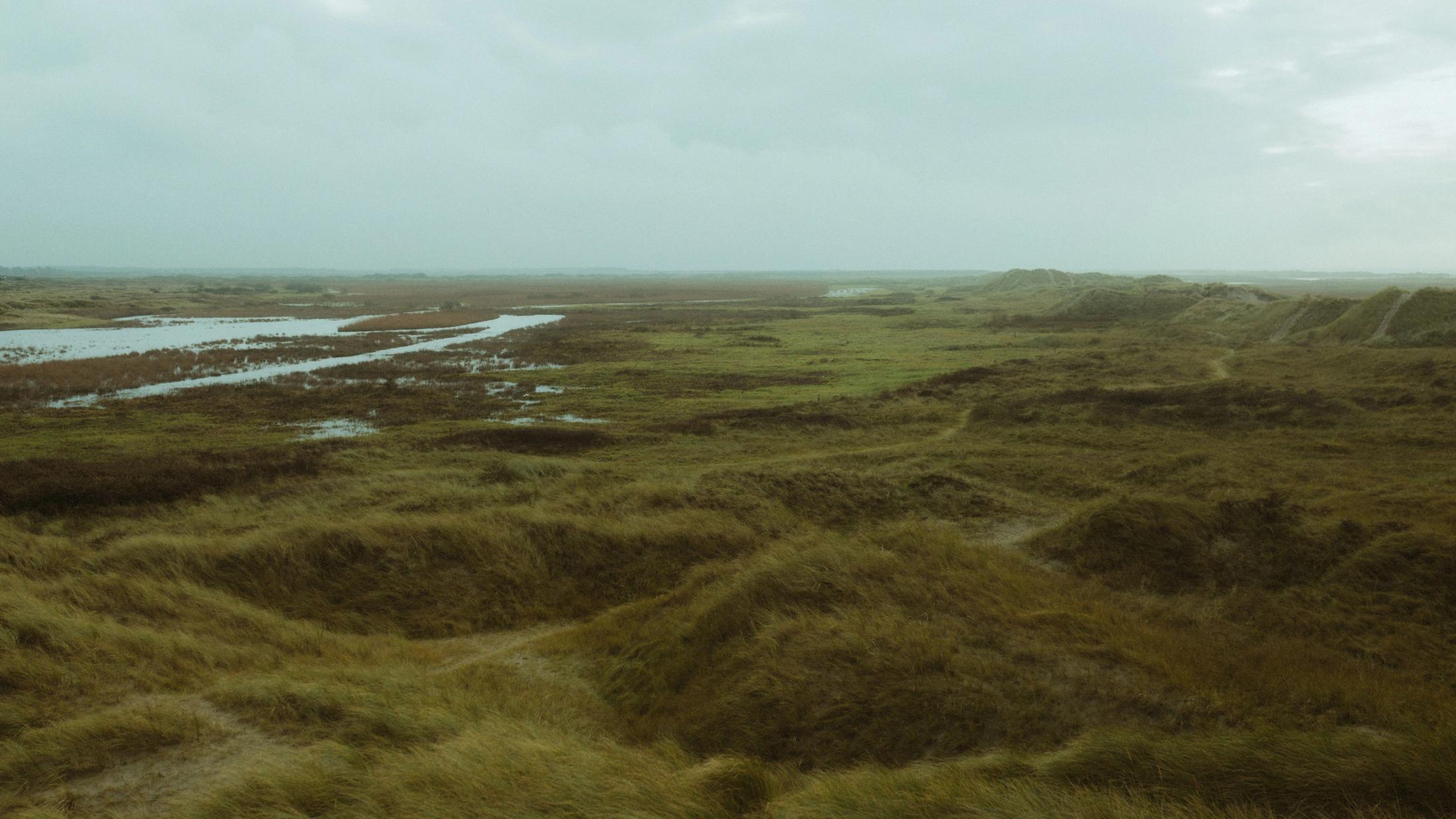 Empty marshland and tidal pools beneath a grey sky on Rømø.