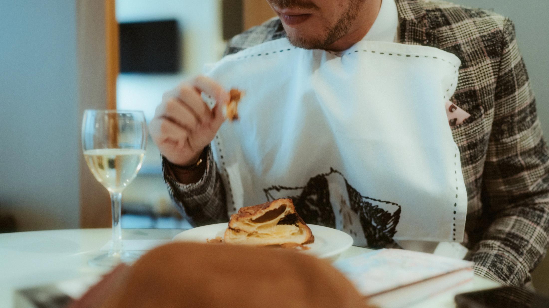 Pia eating a pastry with a napkin tucked into her collar