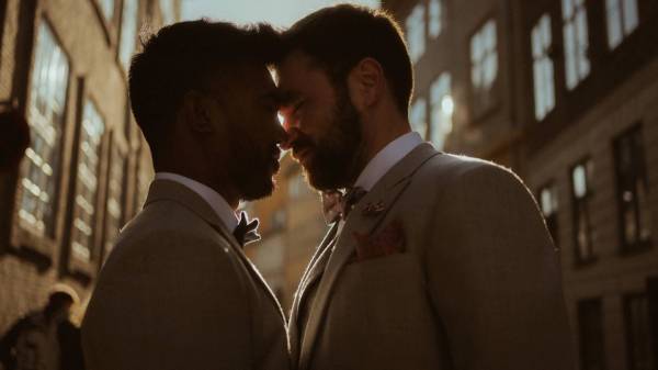 Kris and Ilya touch foreheads in a narrow Copenhagen street, outlined by low evening sun.