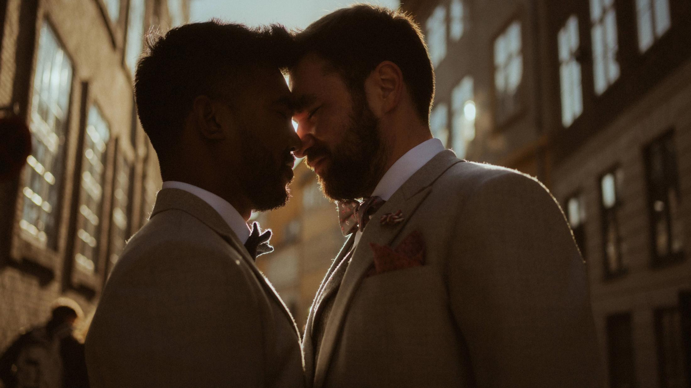 Kris and Ilya touch foreheads in a narrow Copenhagen street, outlined by low evening sun.