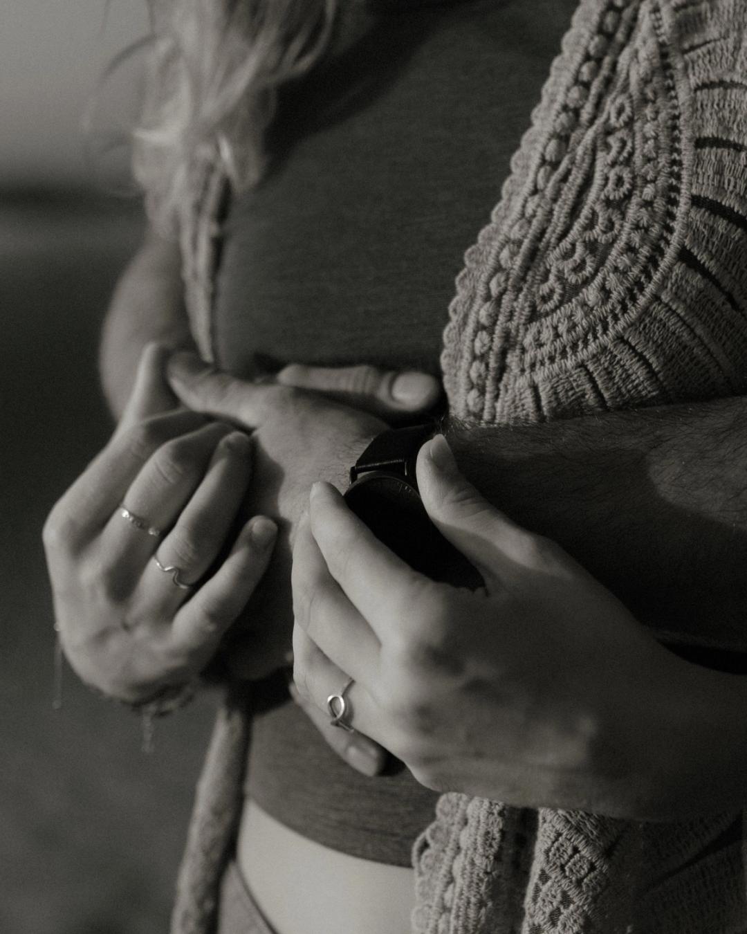 Black-and-white detail of the couple's hands and clothing.