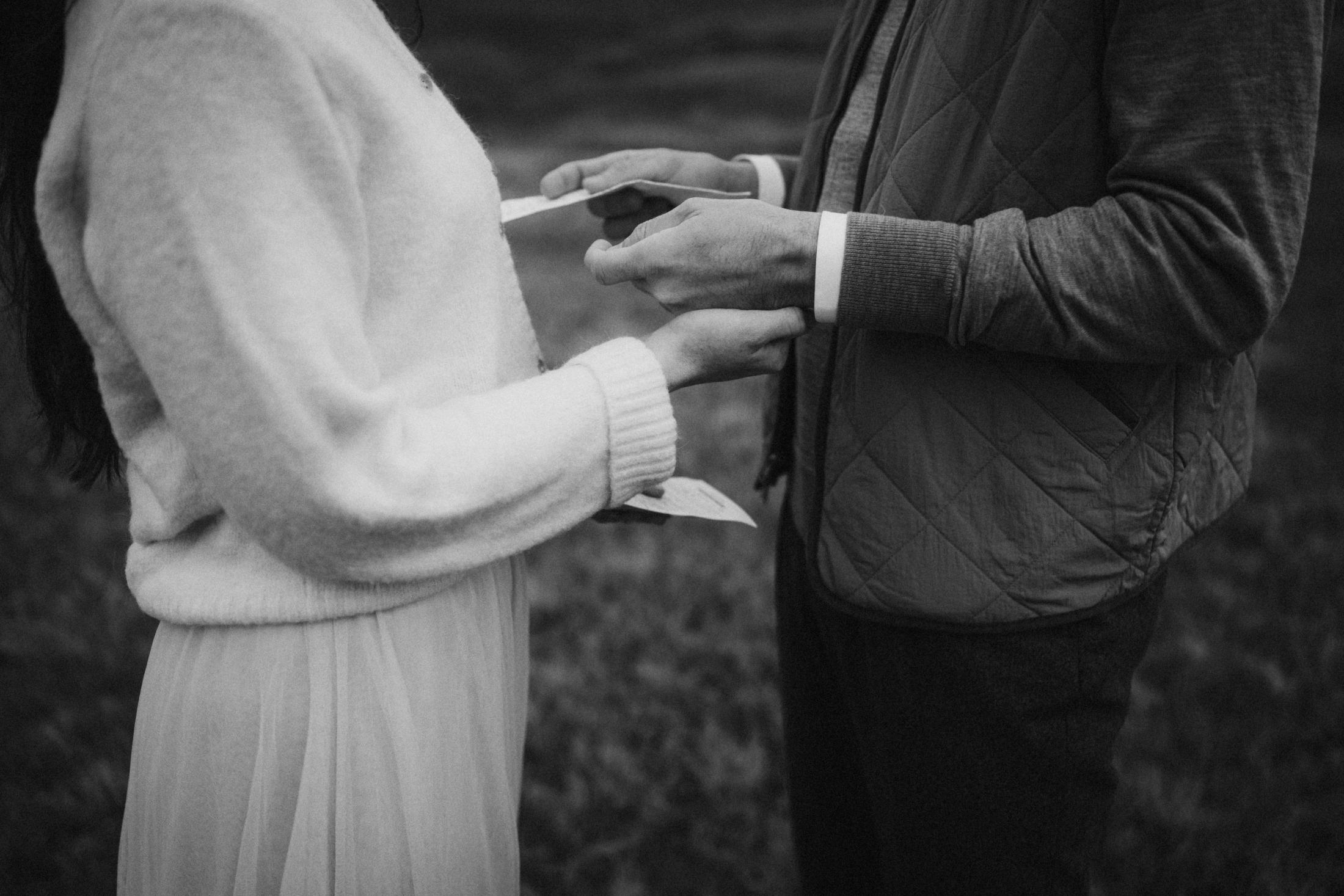 Black-and-white detail of a handwritten vow letter held in both hands.