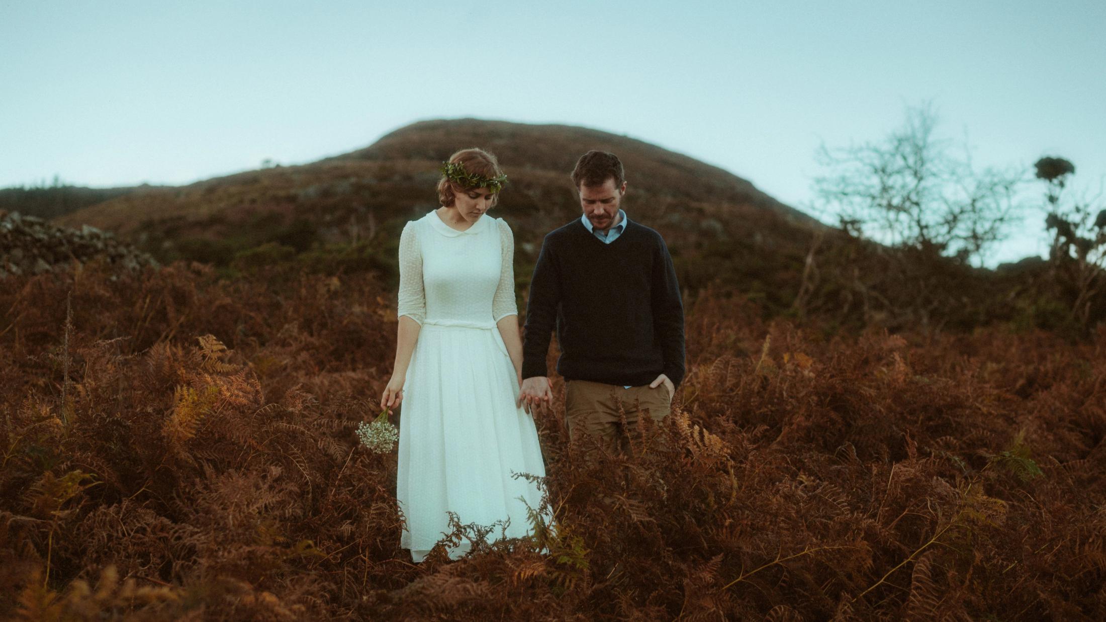 Jule und Rory gehen Hand in Hand durch hohe Farne und Gras.