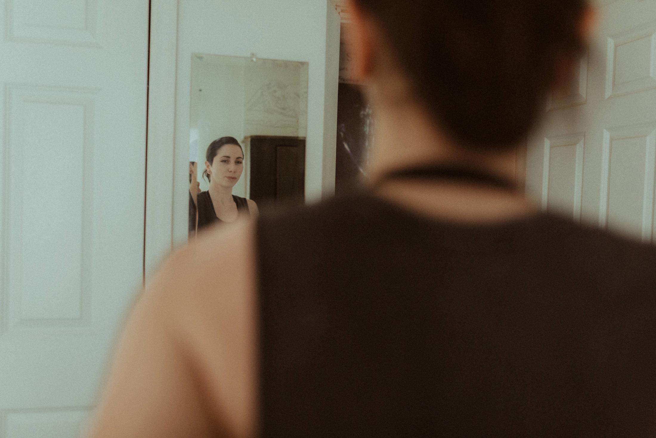 Maya seen in a mirror beyond her own shoulder.