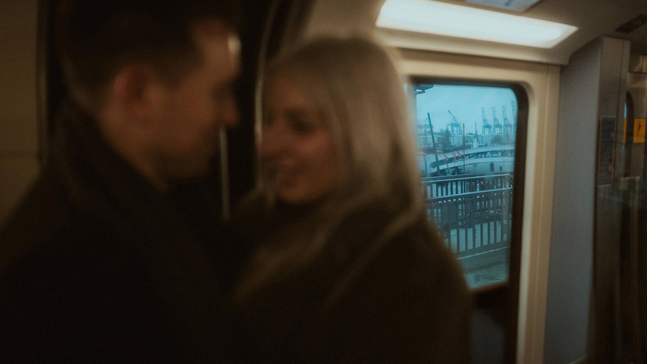 Soft reflection of Lorelai and Steffen beside a U-Bahn window.