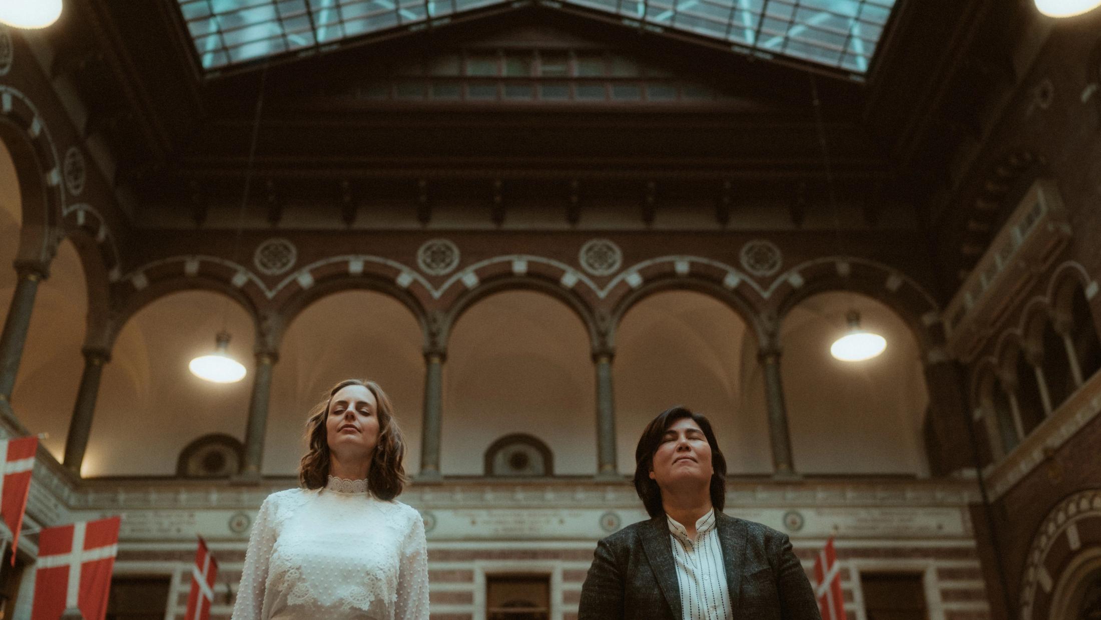 Low-angle portrait of Ari and Pia beneath the atrium