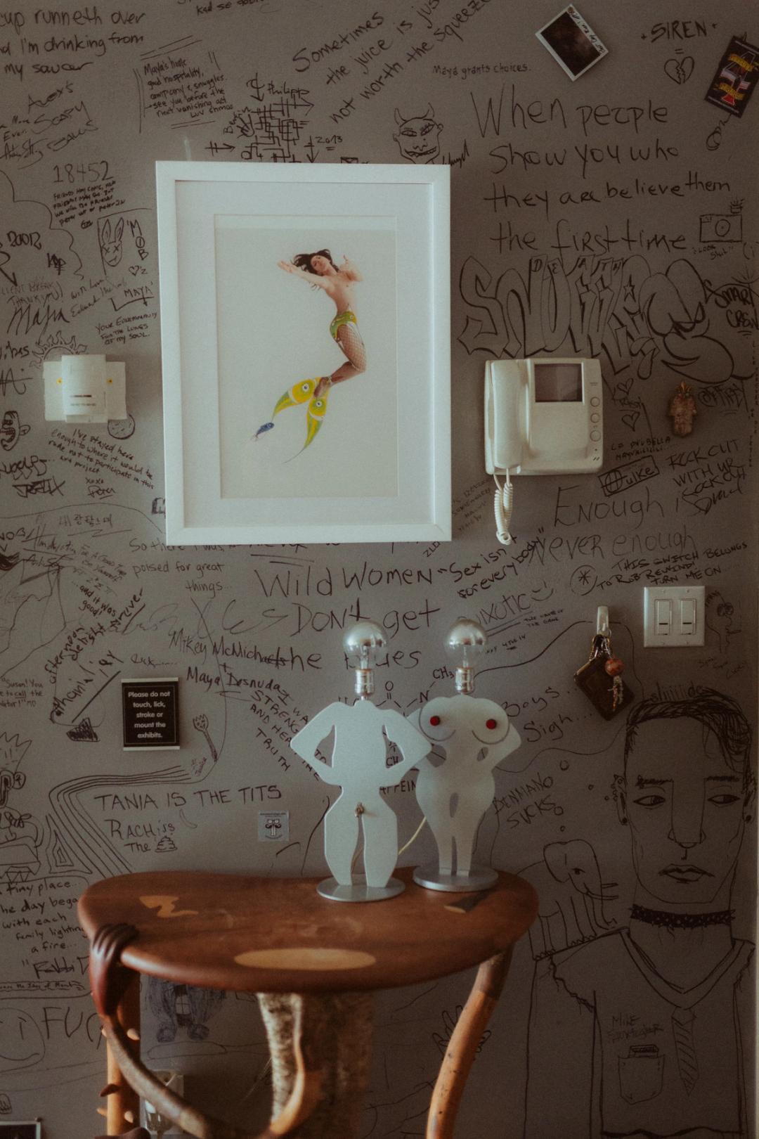 Artwork and personal objects arranged above a chair in Maya’s apartment.