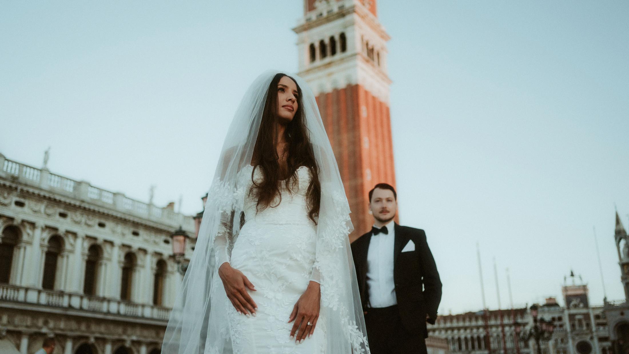 A layered wedding portrait with the bride in front and St Mark's Campanile behind her.