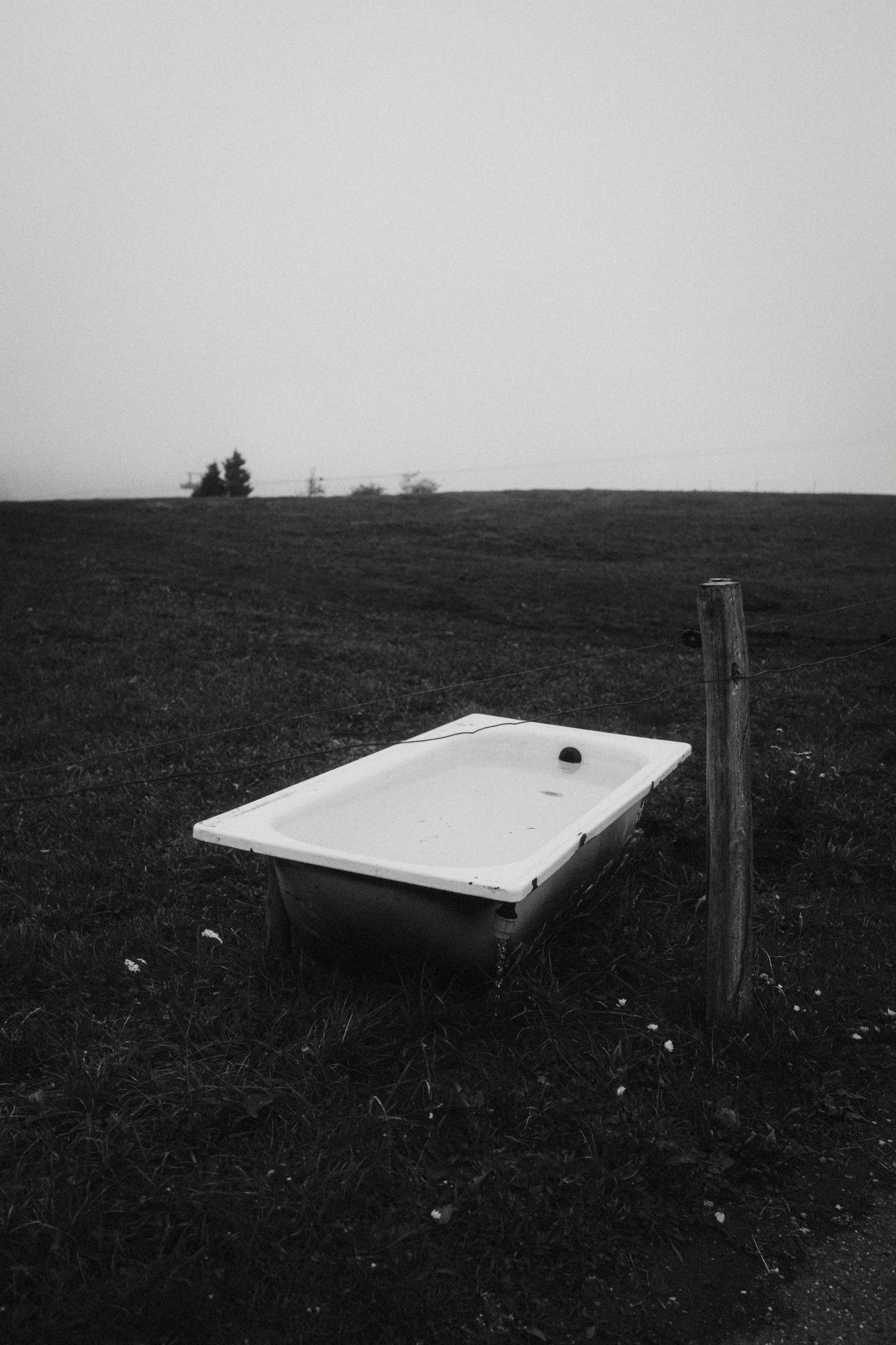 An outdoor bathtub standing alone in thick fog.